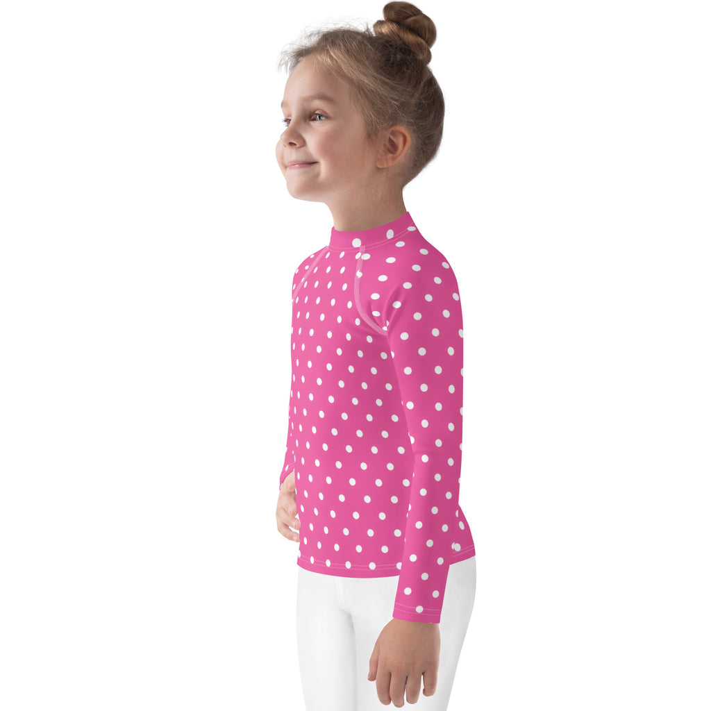 A vibrant pink girls long-sleeve rash guard swim shirt with white polka dots and UPF 50 plus sun protection