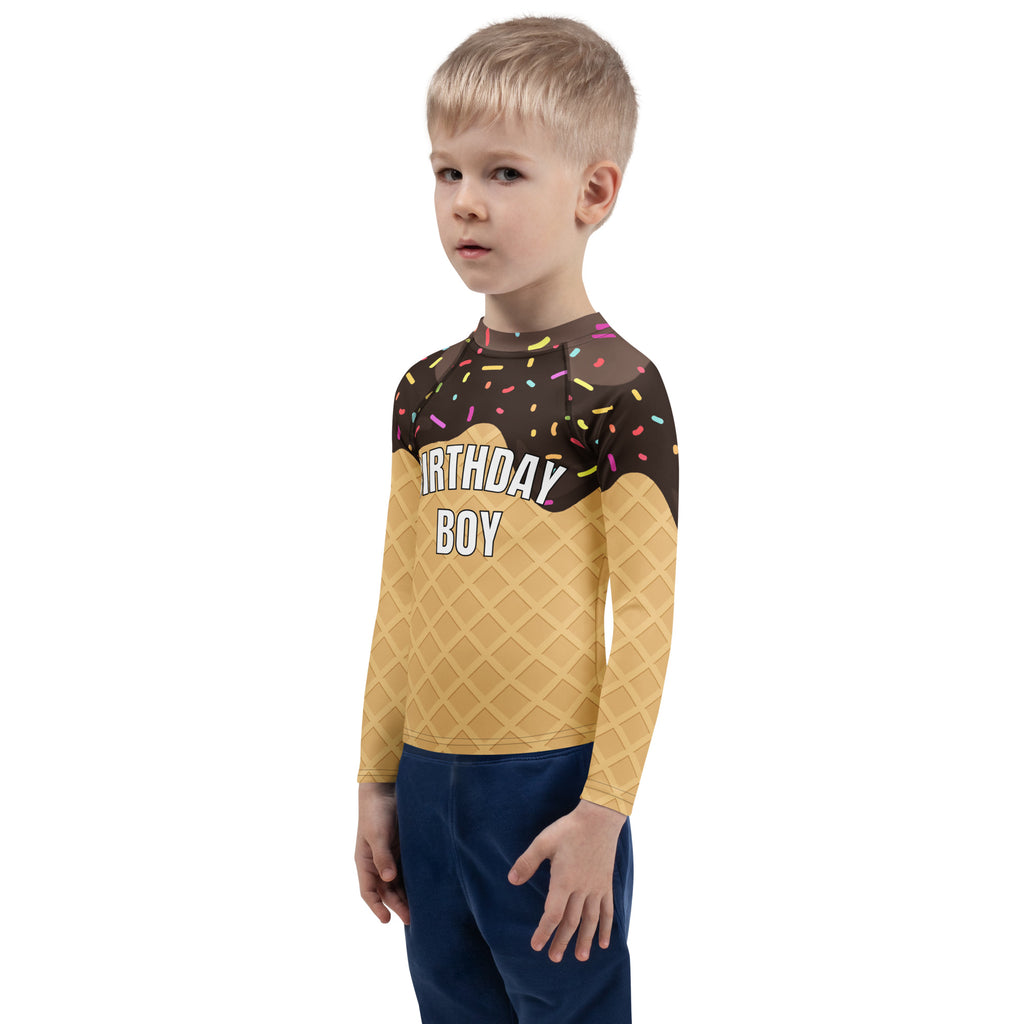 A child wearing a birthday boy chocolate ice cream cone long sleeve rash guard swim shirt with colorful sprinkles and upf 50+ protection