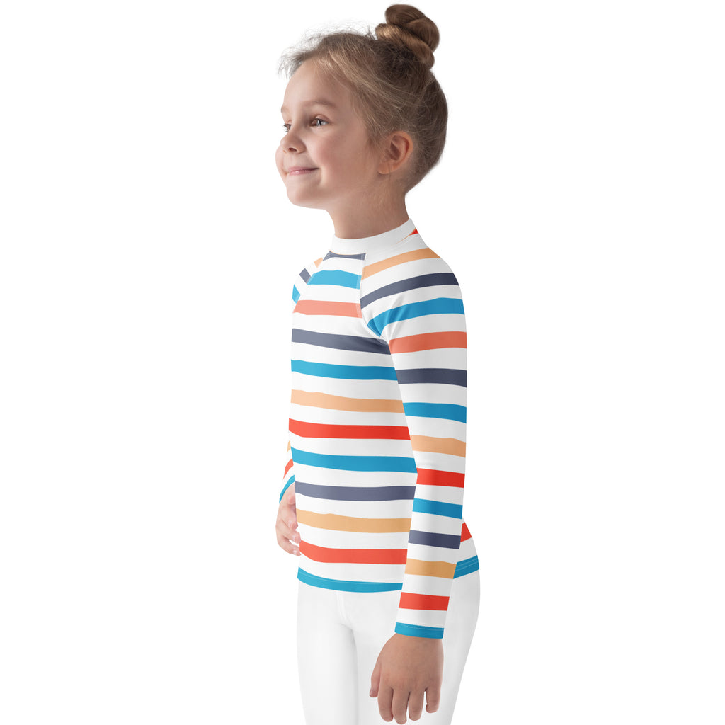 A child wearing a kids coastal stripes long sleeve rash guard swim shirt with upf 50 plus in white orange red blue and navy