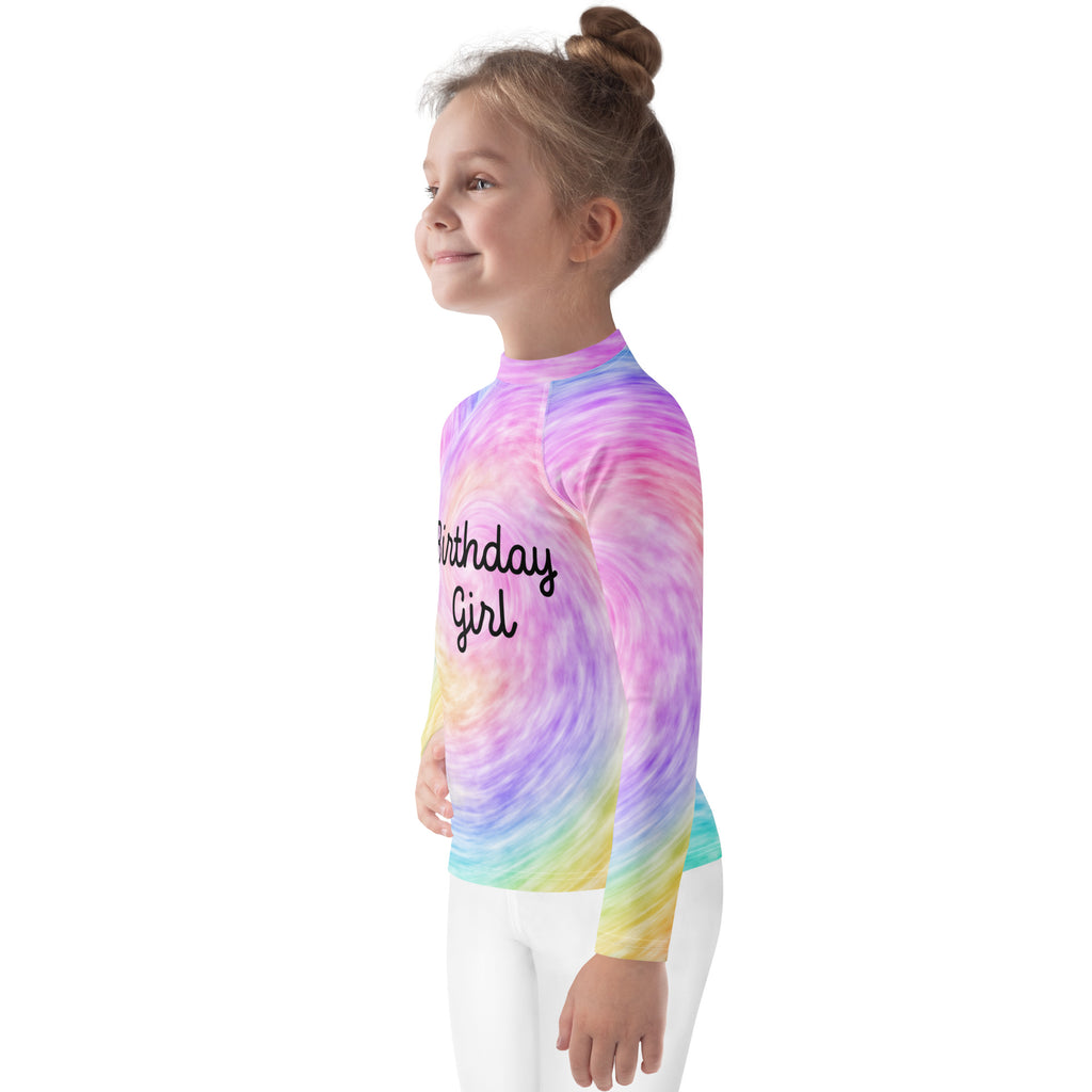 A vibrant rainbow tie dye long sleeve girls rash guard with birthday girl print and UPF 50 plus for swim protection