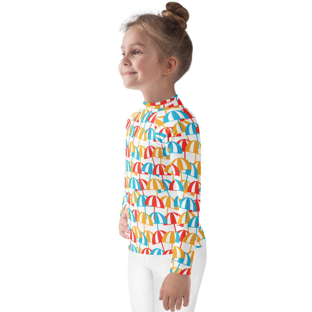 A child wearing a long-sleeved white rash guard with colorful umbrella prints for sun protection upf 50+ beach swim shirt