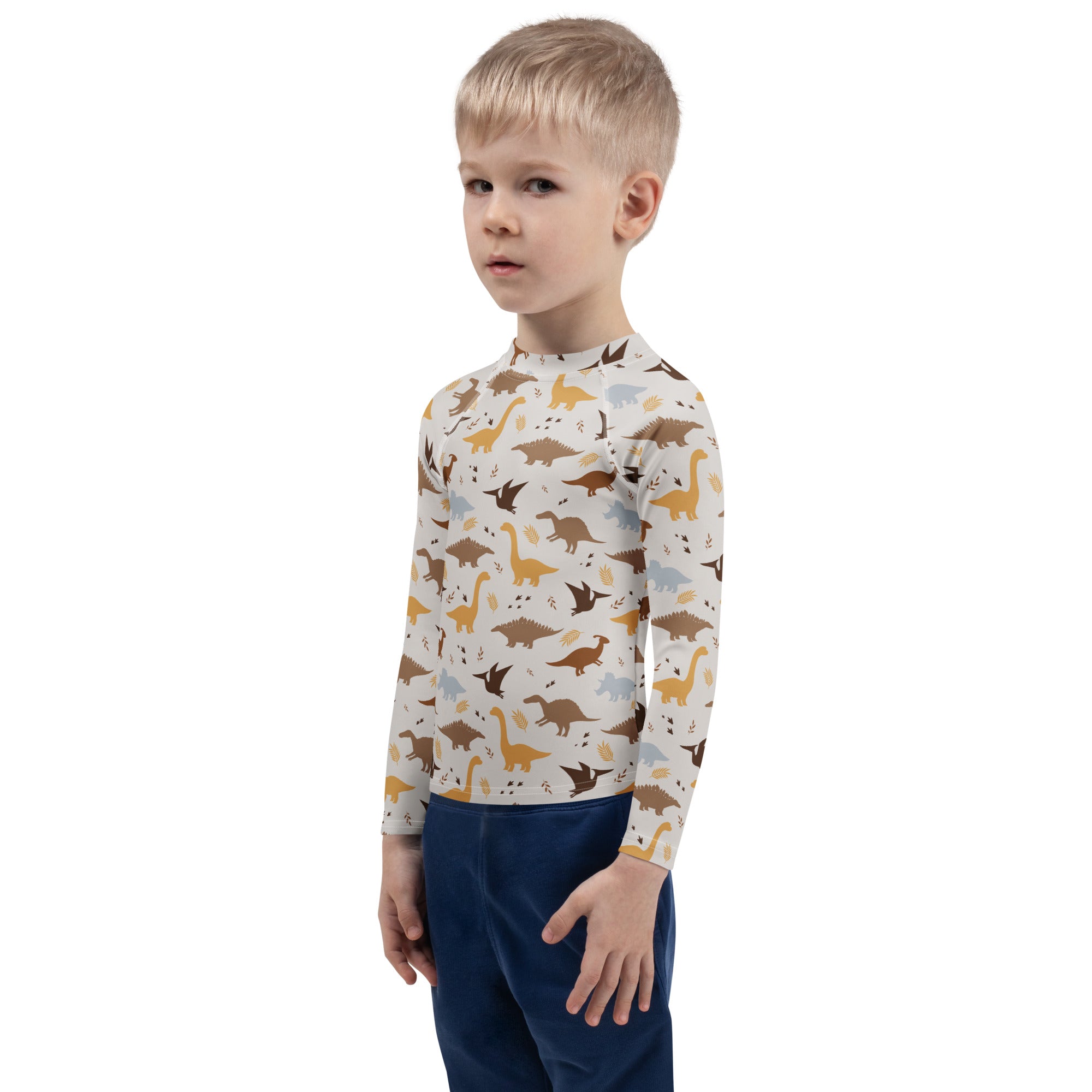 A child wearing a cream kids dinosaur long sleeve rash guard swim shirt with playful brown and yellow dino patterns and UPF 50+