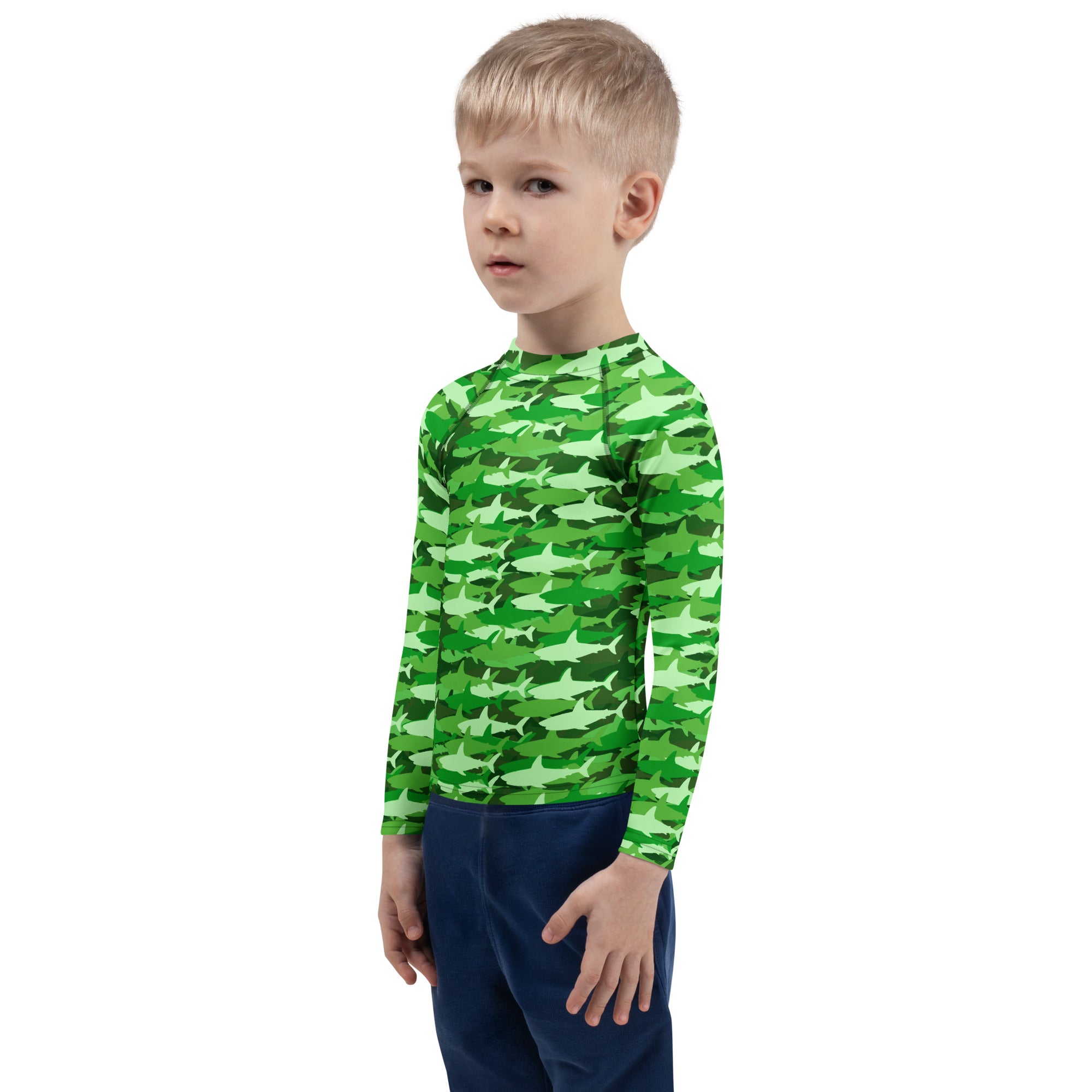 A child wearing a kids green shark long sleeve rash guard swim shirt with UPF 50 plus for sun protection