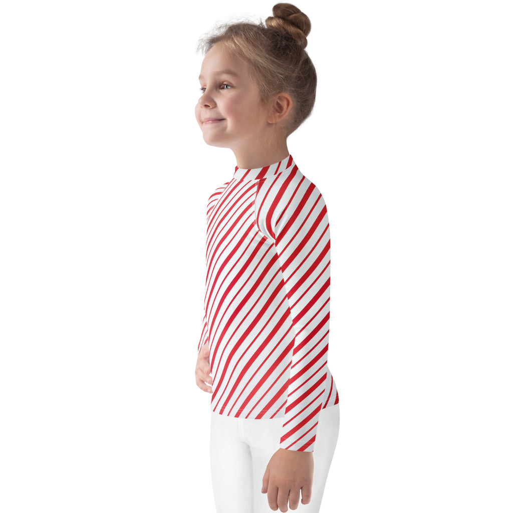 A child wearing a kids red and white candy cane striped long sleeve rash guard swim shirt with UPF 50 plus