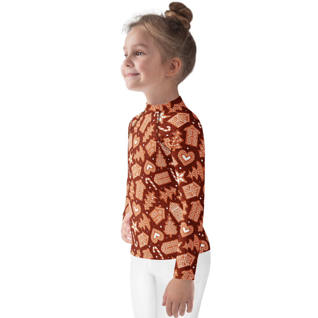 A child wears a festive brown kids red gingerbread Christmas long sleeve rash guard swim shirt with UPF 50+ and holiday patterns