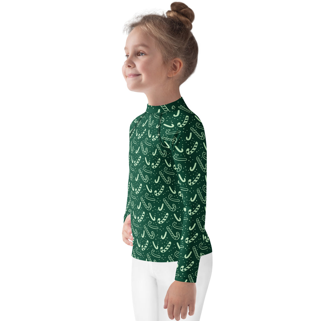 A child wearing a kids green candy cane Christmas long sleeve rash guard swim shirt with UPF 50 plus protection