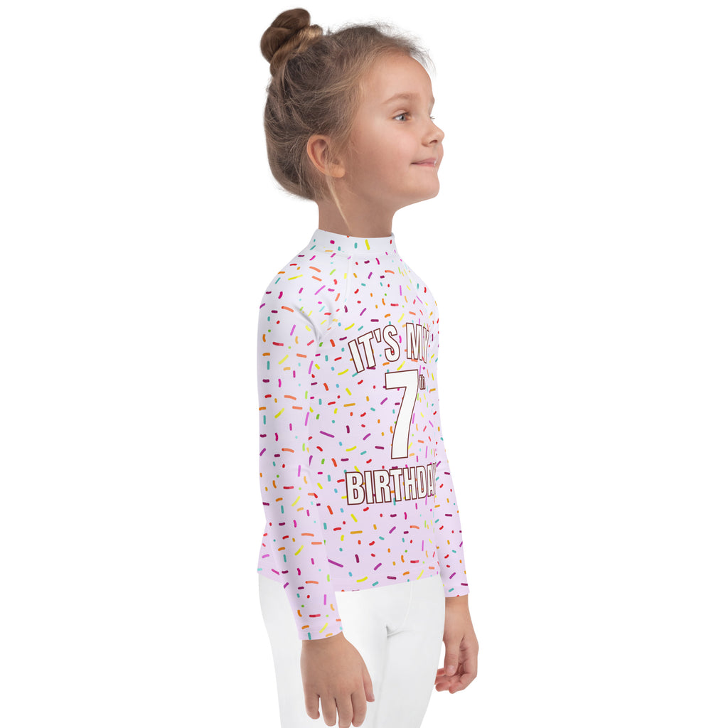 A child’s long-sleeved white rash guard swim shirt with colorful sprinkles and custom age text for 7th birthday