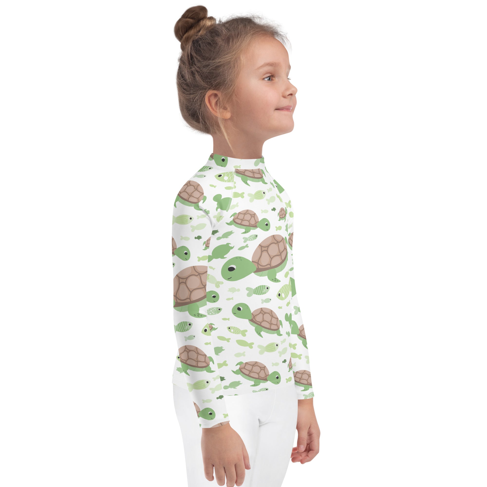 A white long-sleeved kids rash guard with green and brown turtles and small fish swim shirt with UPF 50+ protection
