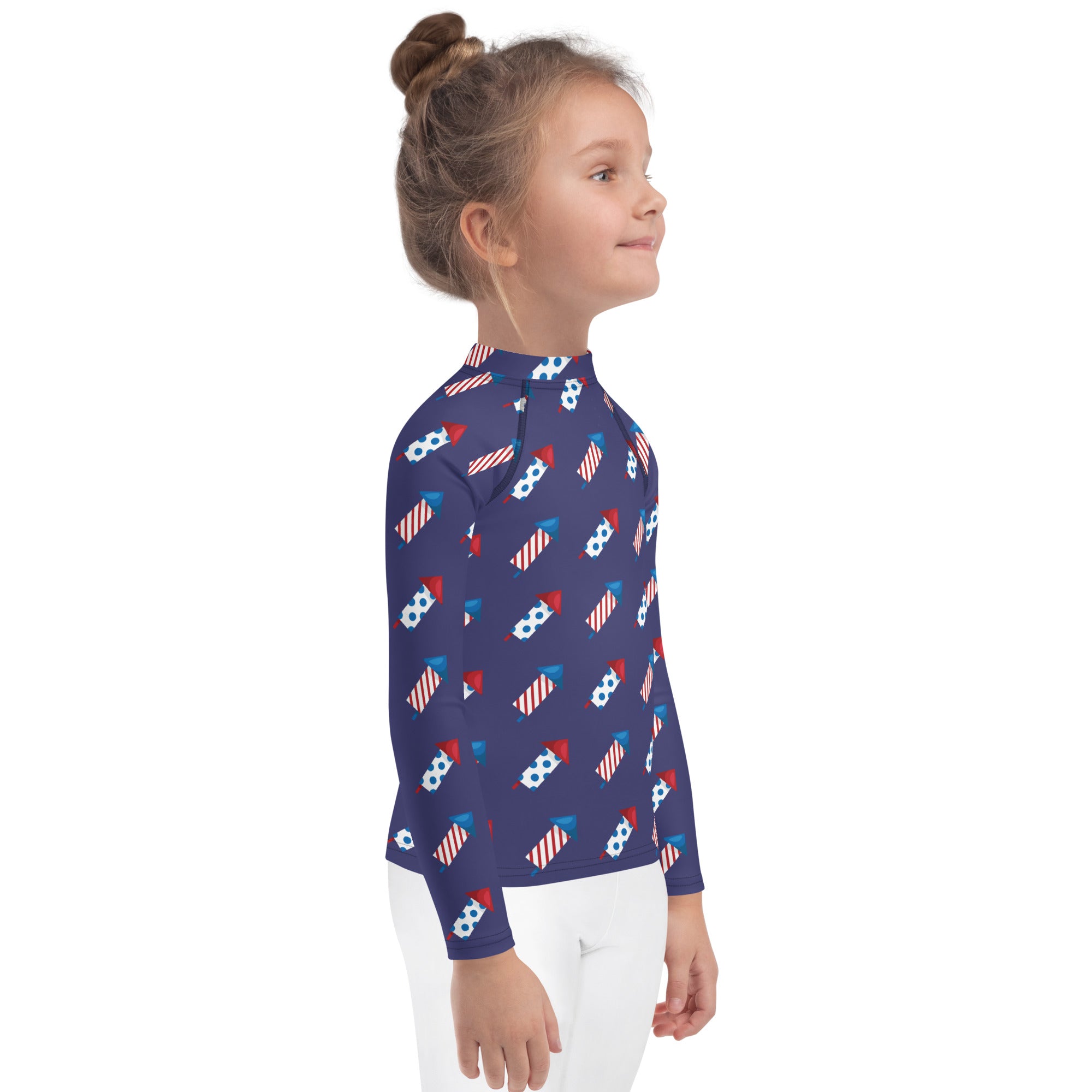 A navy blue kids long sleeve rash guard swim shirt with red white and blue fireworks pattern and UPF 50 plus protection