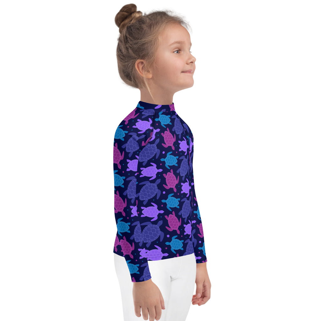 A girls navy blue long sleeve rash guard with a vibrant purple pink and teal sea turtle pattern and UPF 50+ protection