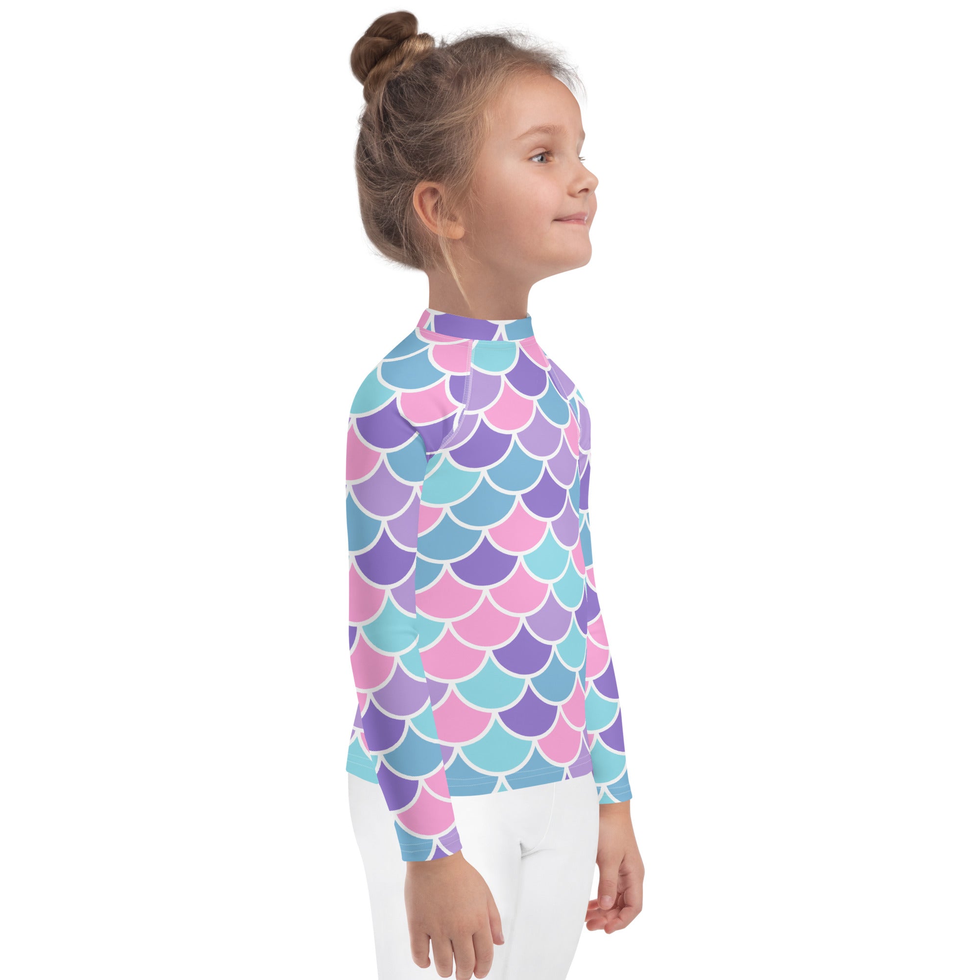A child wearing a girls pastel mermaid scales long sleeve rash guard swim shirt with vibrant pink purple teal pattern and upf 50+