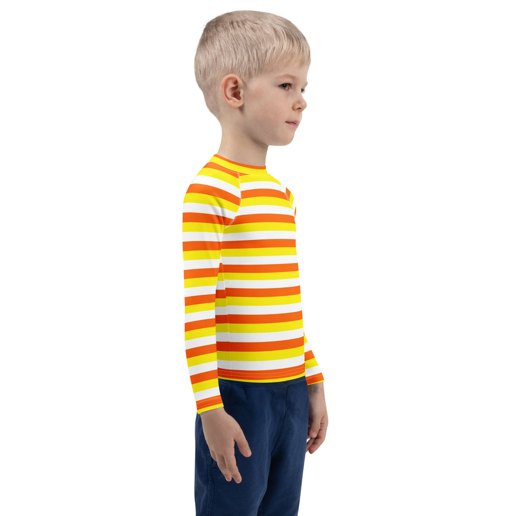 A child wearing a kids candy corn stripes halloween long sleeve rash guard swim shirt with upf 50+ in bright orange yellow and white