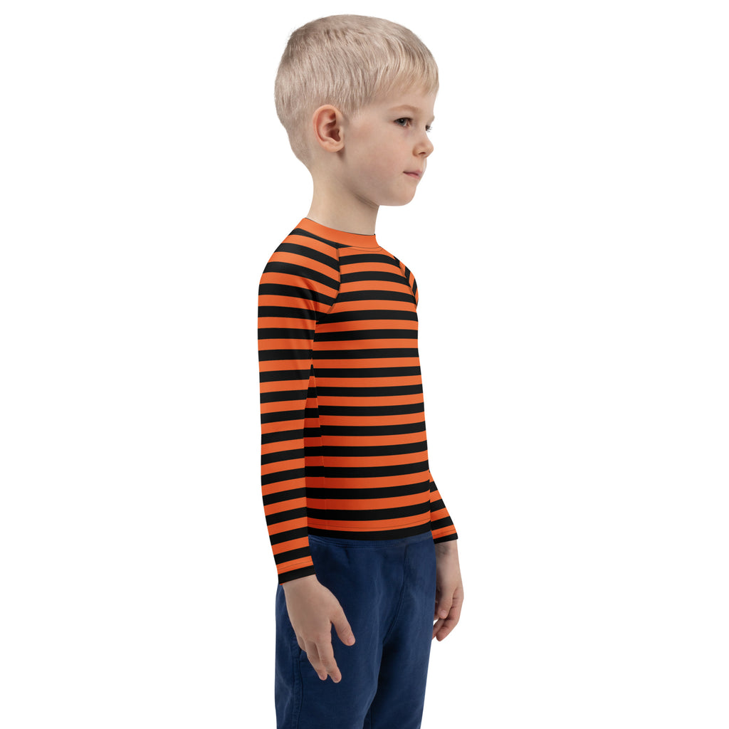 A child wearing a kids orange and black halloween long sleeve rash guard swim shirt with UPF 50+ protection
