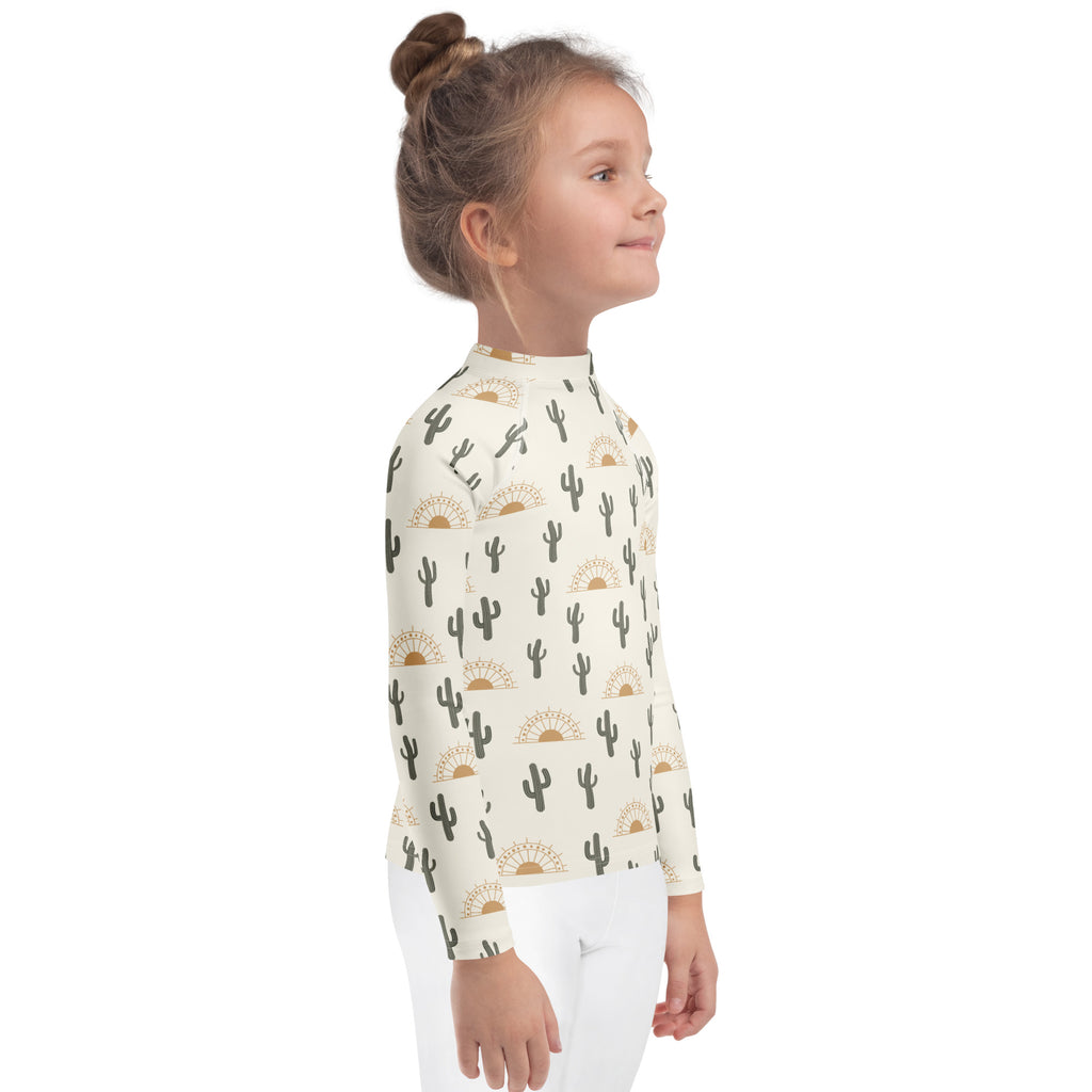 Kids cactus desert sunrise long sleeve rash guard swim shirt in cream fabric with black cacti and tan sunburst print
