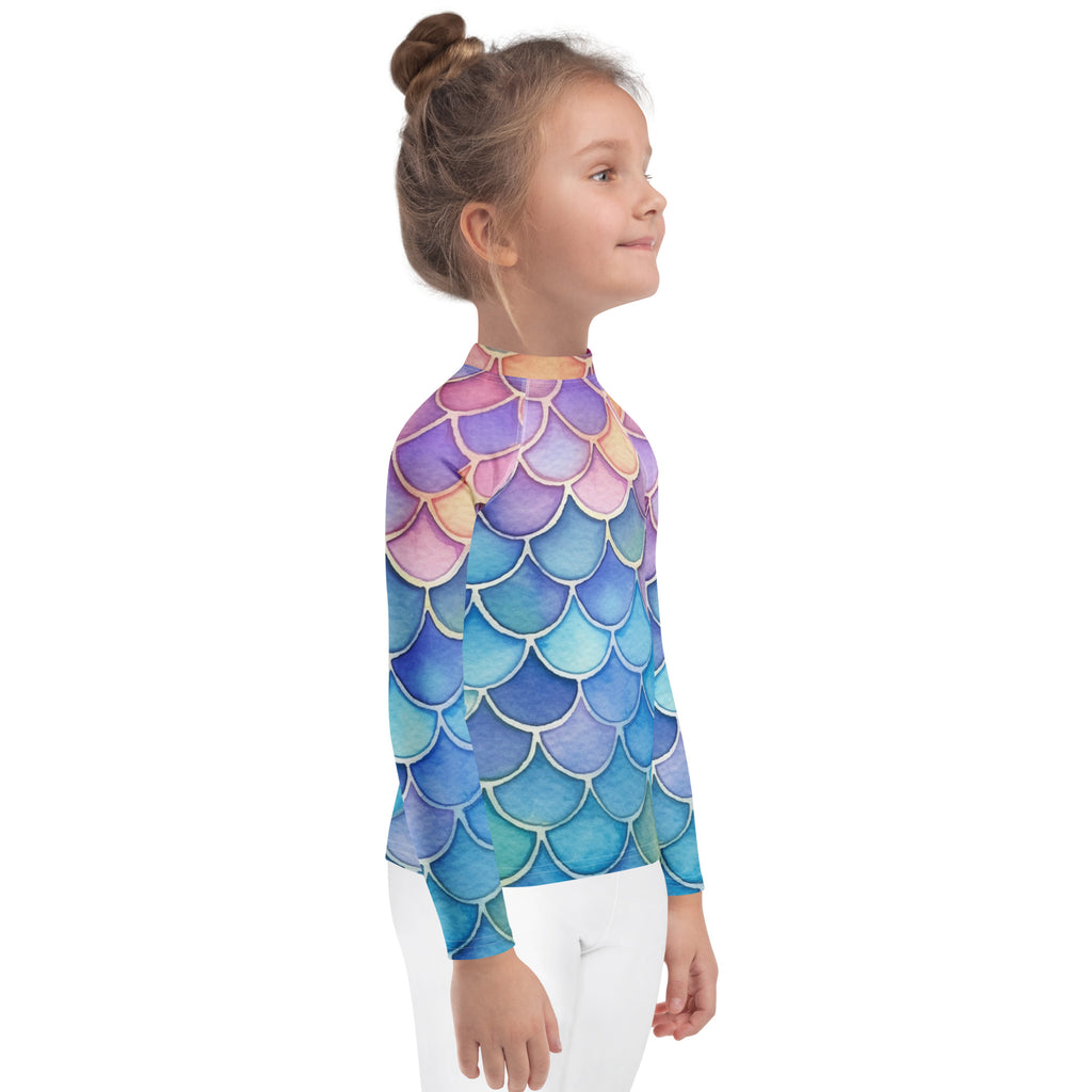 A child wearing a girls watercolor rainbow mermaid long sleeve rash guard swim shirt with upf 50 plus in purple pink blue and teal