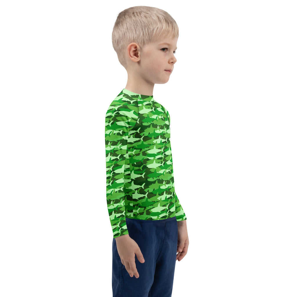 A child wearing a kids green shark long sleeve rash guard swim shirt with UPF 50 plus for sun protection