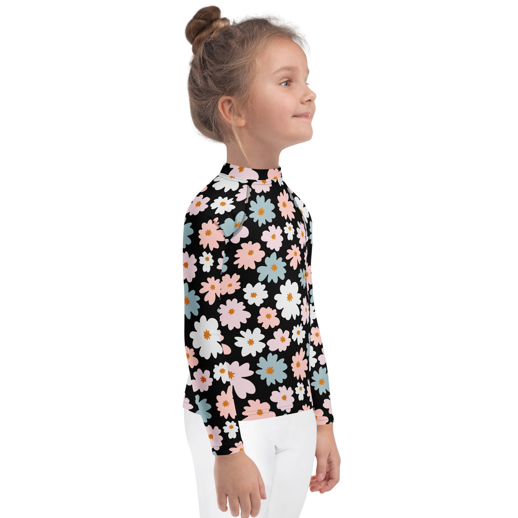 A black girls long sleeve rash guard swim shirt with vibrant pink white and blue daisies and upf 50 plus protection