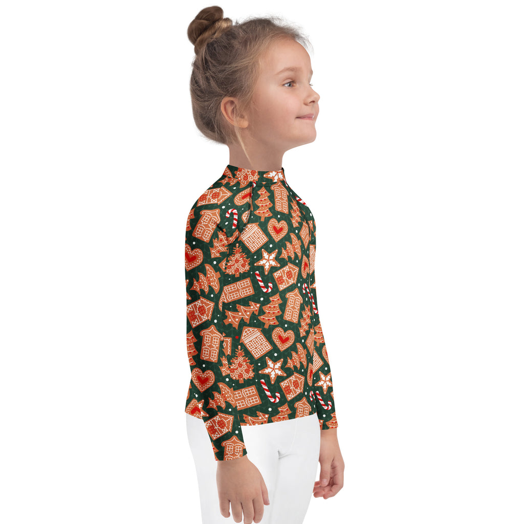 A child wearing a kids green gingerbread christmas long sleeve rash guard swim shirt with upf 50 and festive pattern