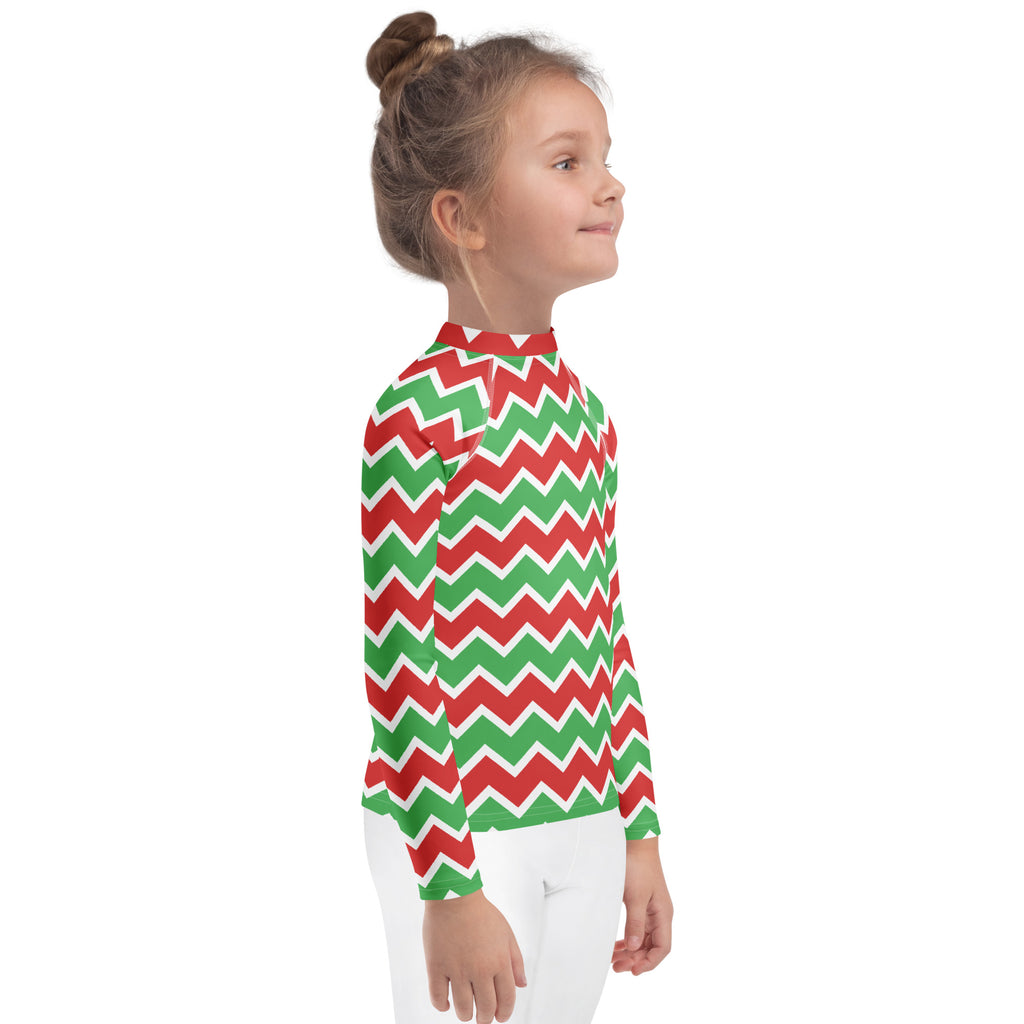 A child wearing a kids christmas chevron long sleeve rash guard swim shirt with red and green zigzag pattern and UPF 50+
