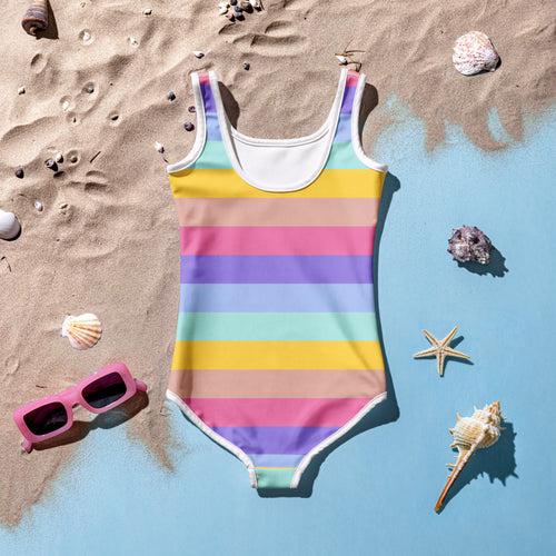 A girls colorful stripes buttery soft one-piece swimsuit with white trim and upf 50 plus on sandy beach