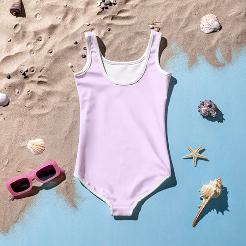 A soft lavender girls cute corgi dog one-piece swimsuit with white trim and buttery soft fabric laid flat on sand