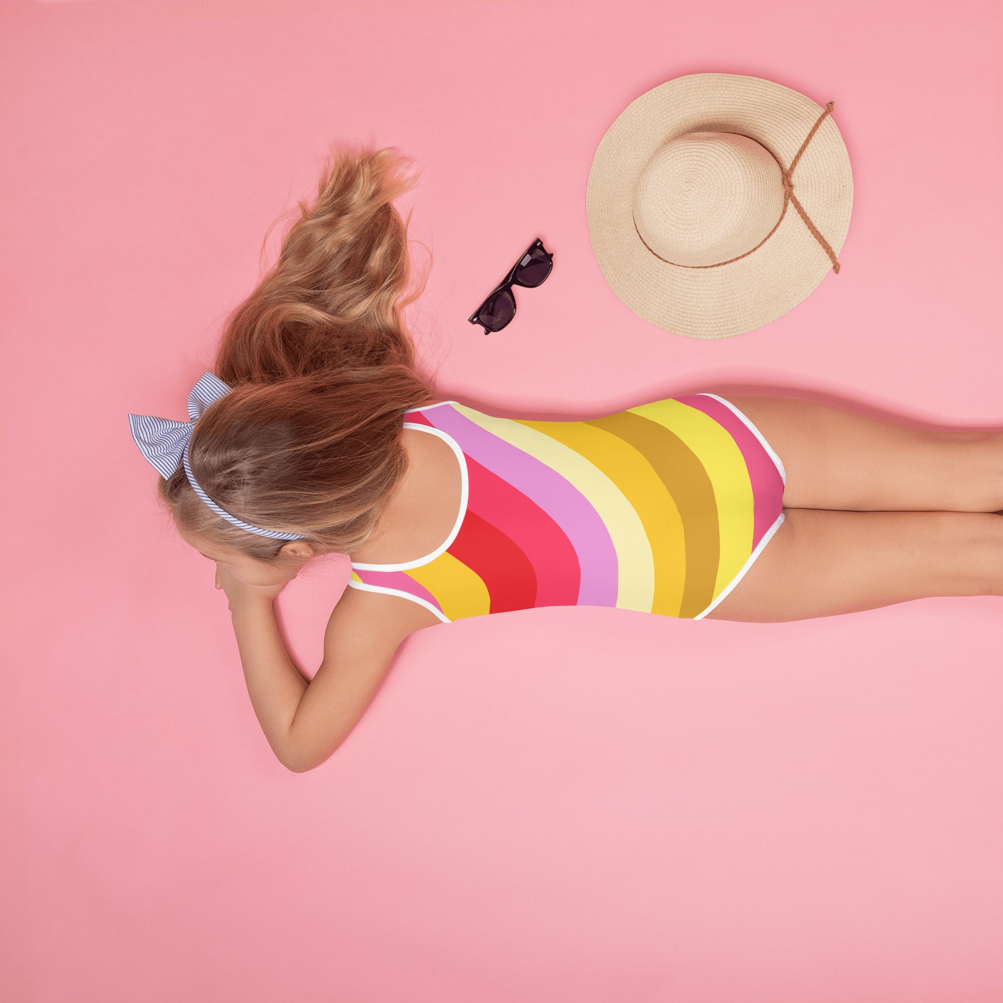 A vibrant girls one-piece swimsuit with bold pink yellow purple and red stripes buttery soft fabric and UPF 50+ protection