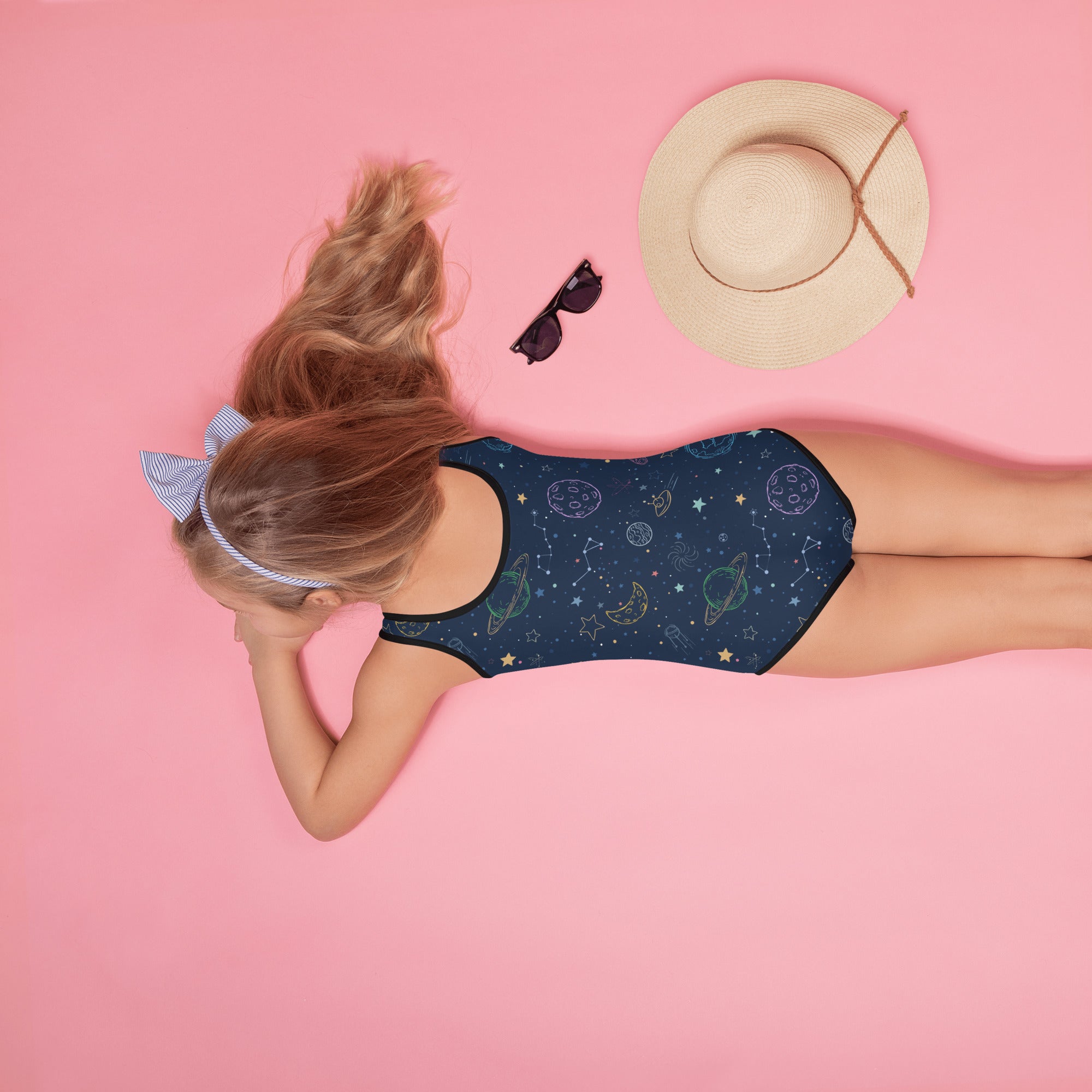 A navy blue girls one-piece swimsuit with buttery soft fabric and celestial planets stars and moons pattern with UPF 50+