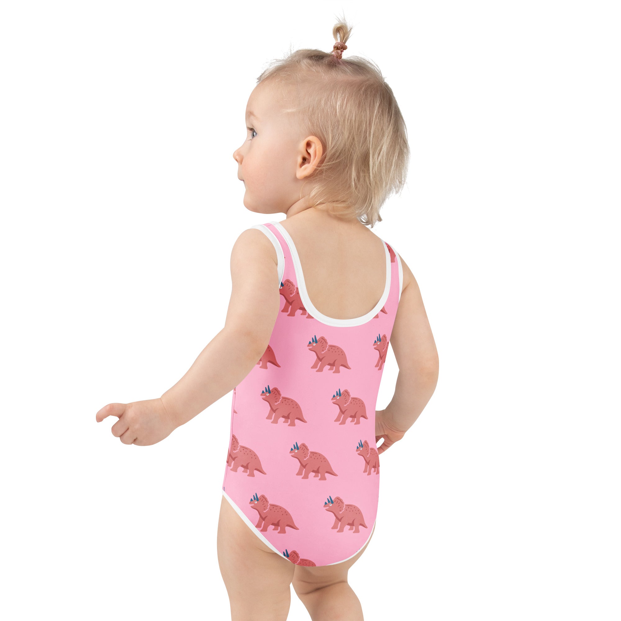 Girls pink buttery soft one-piece swimsuit with white trim and cartoon triceratops pattern and upf 50 plus protection