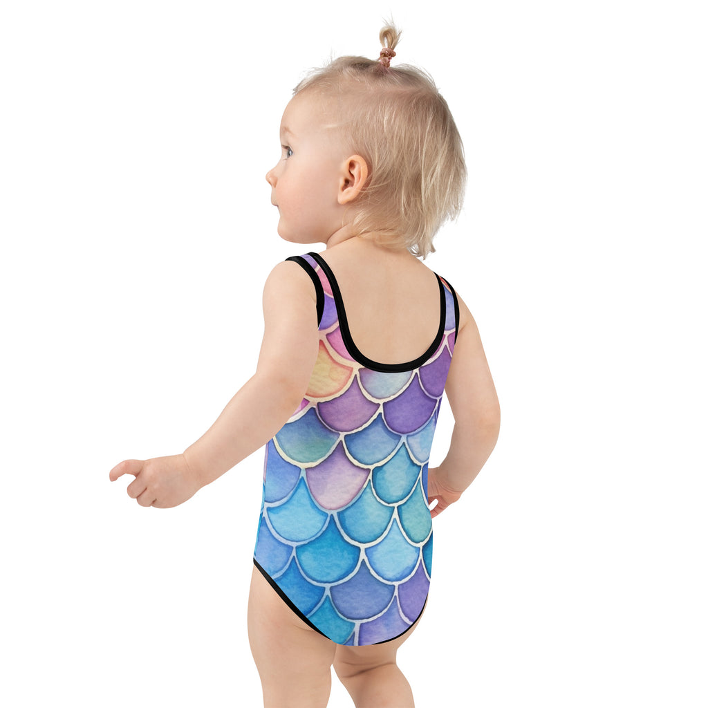 A child wearing a girls watercolor mermaid scales buttery soft swimsuit in blue purple and pink with black trim and upf 50+