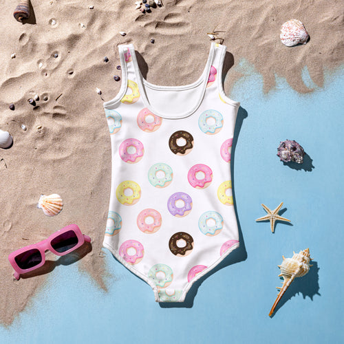 A white one-piece swimsuit with colorful pastel and chocolate donut pattern featuring thin straps and rounded neckline