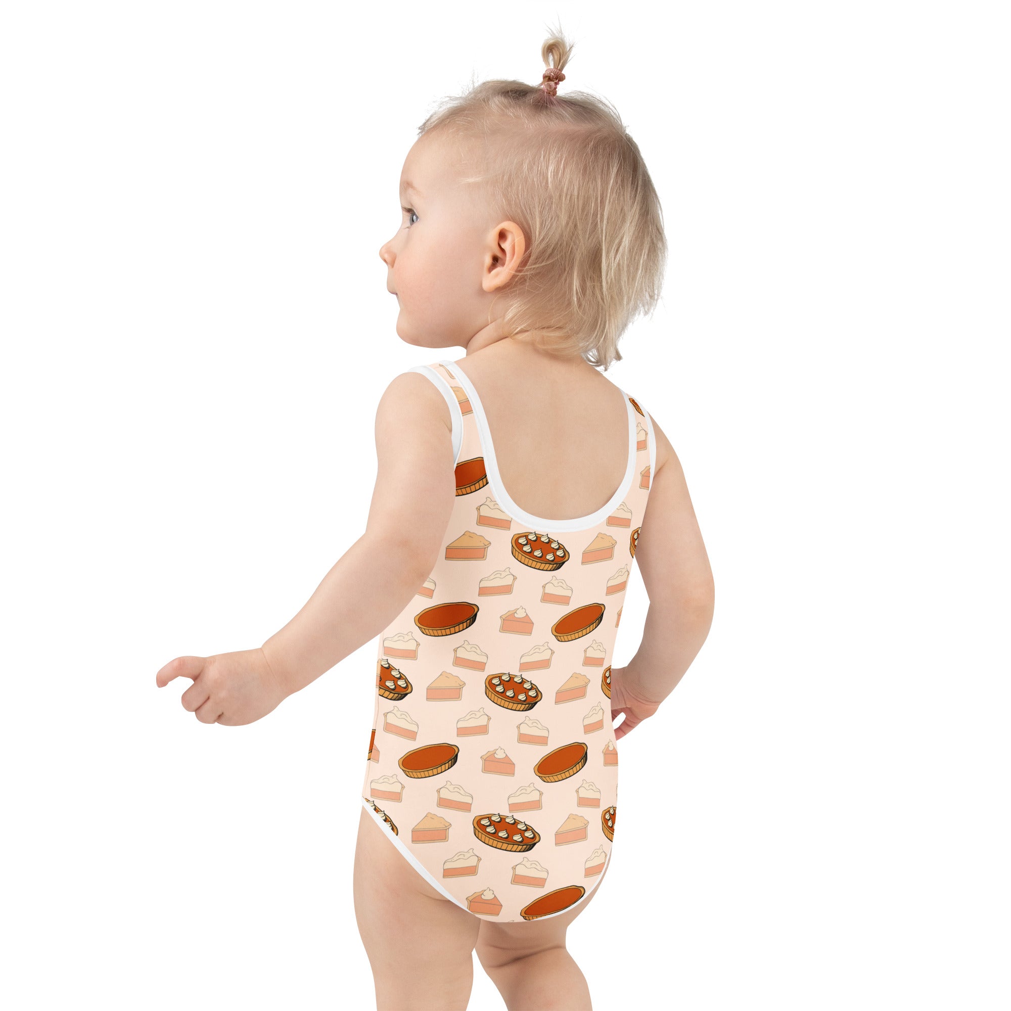 A toddler wearing a peach girls pumpkin pie thanksgiving buttery soft swimsuit with upf 50 plus and pie slice print