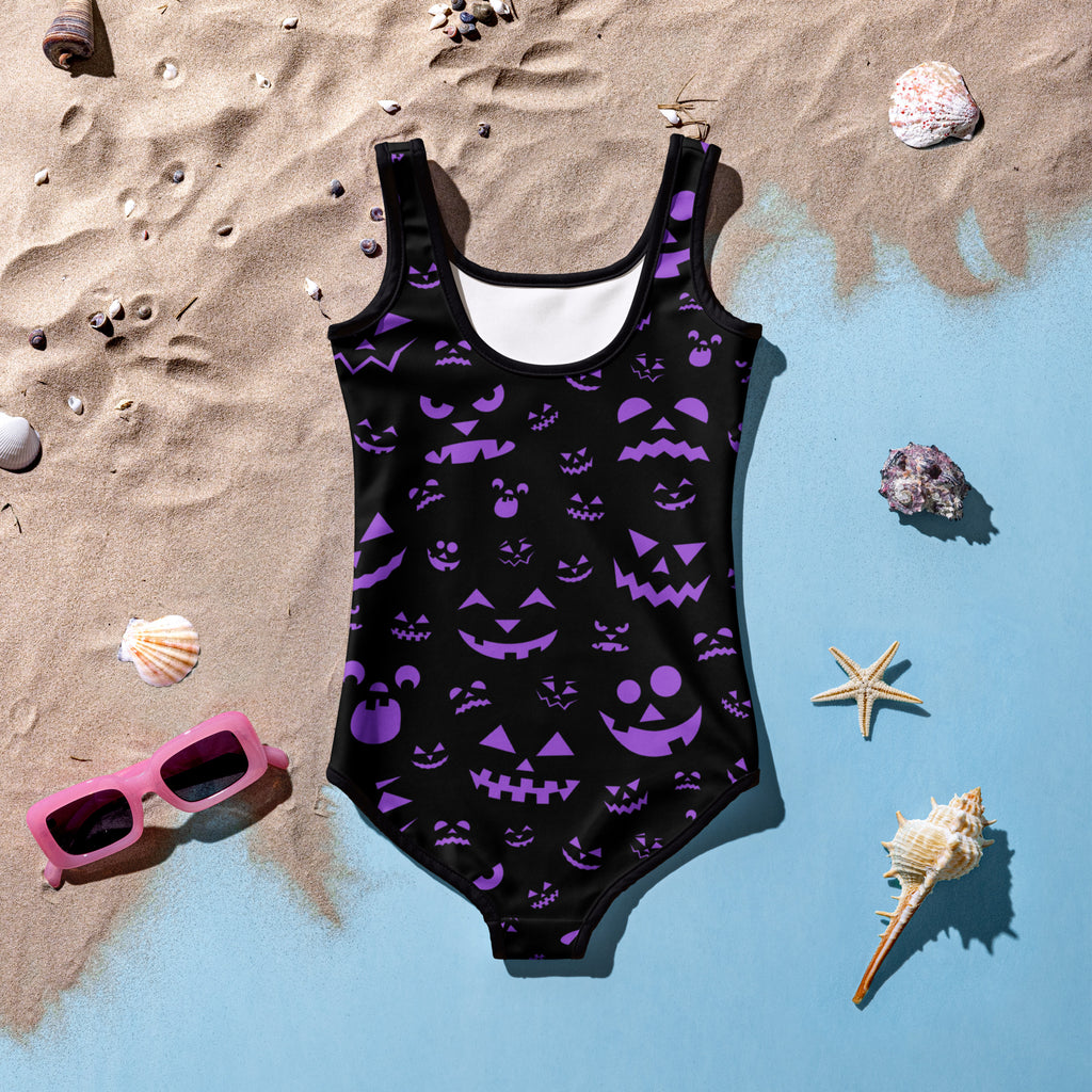 Girls purple jack-o-lantern faces halloween swimsuit featuring a black one-piece with purple pumpkin prints