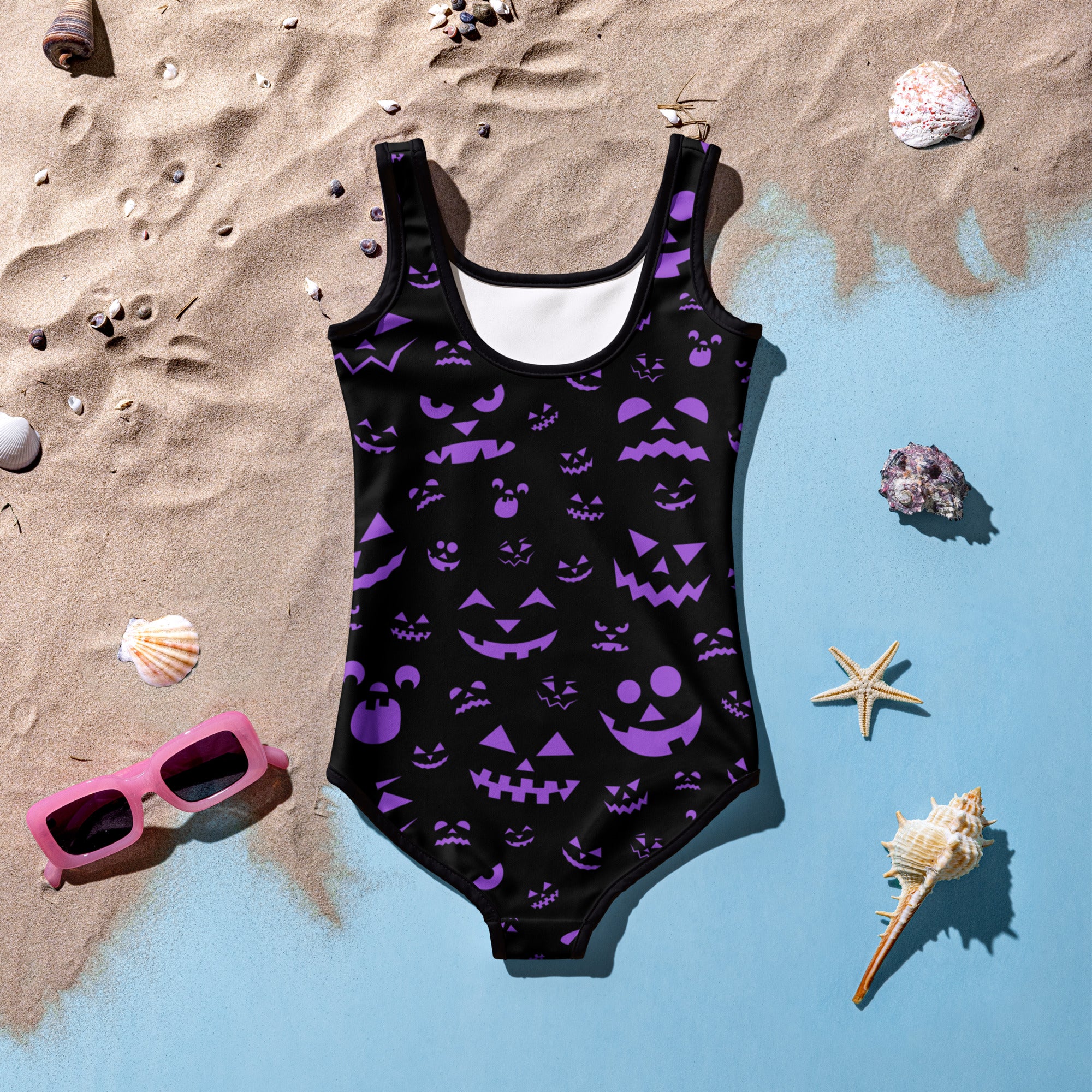 Girls purple jack-o-lantern faces halloween swimsuit featuring a black one-piece with purple pumpkin prints