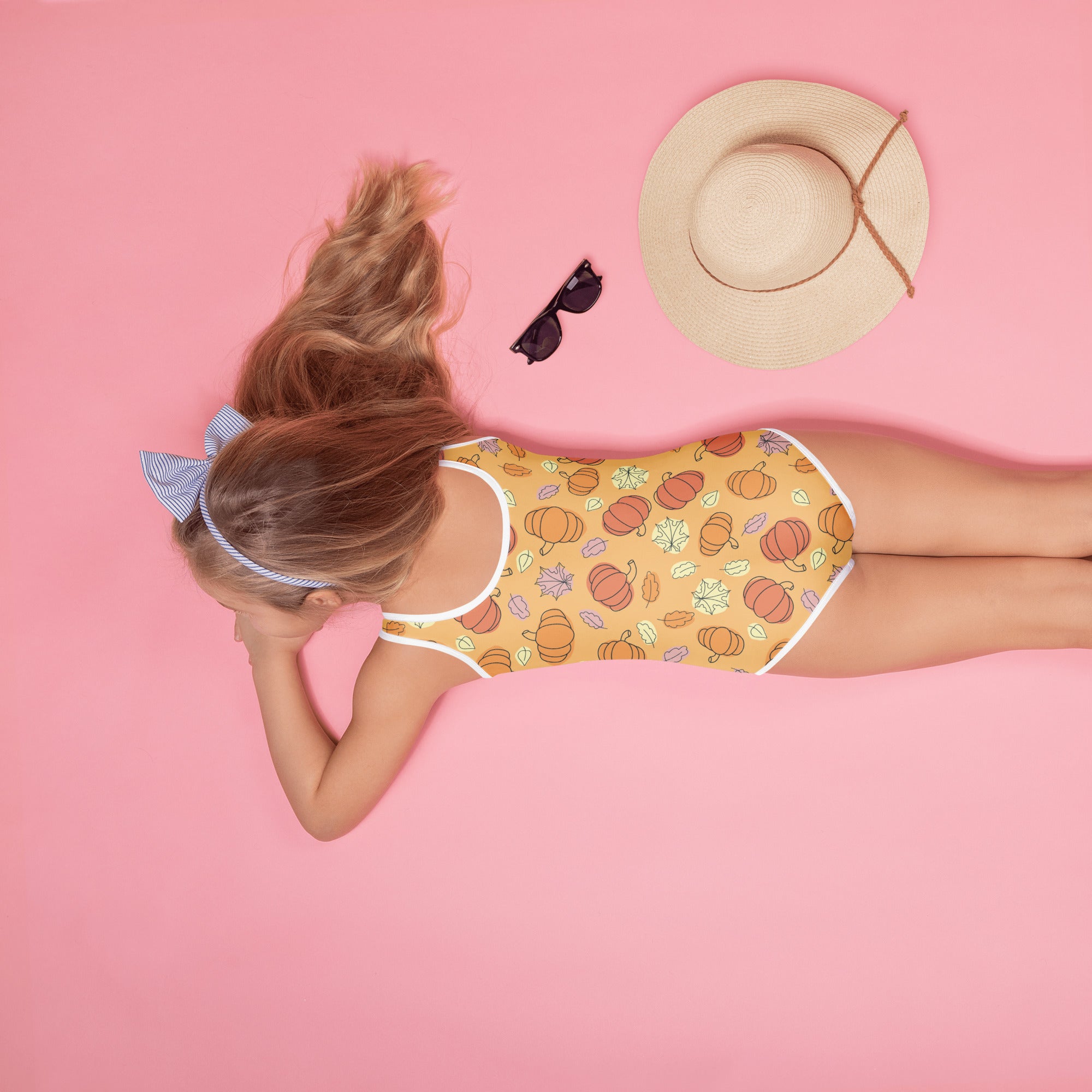 Person wearing a swimsuit with a pumpkin pattern on a pink background