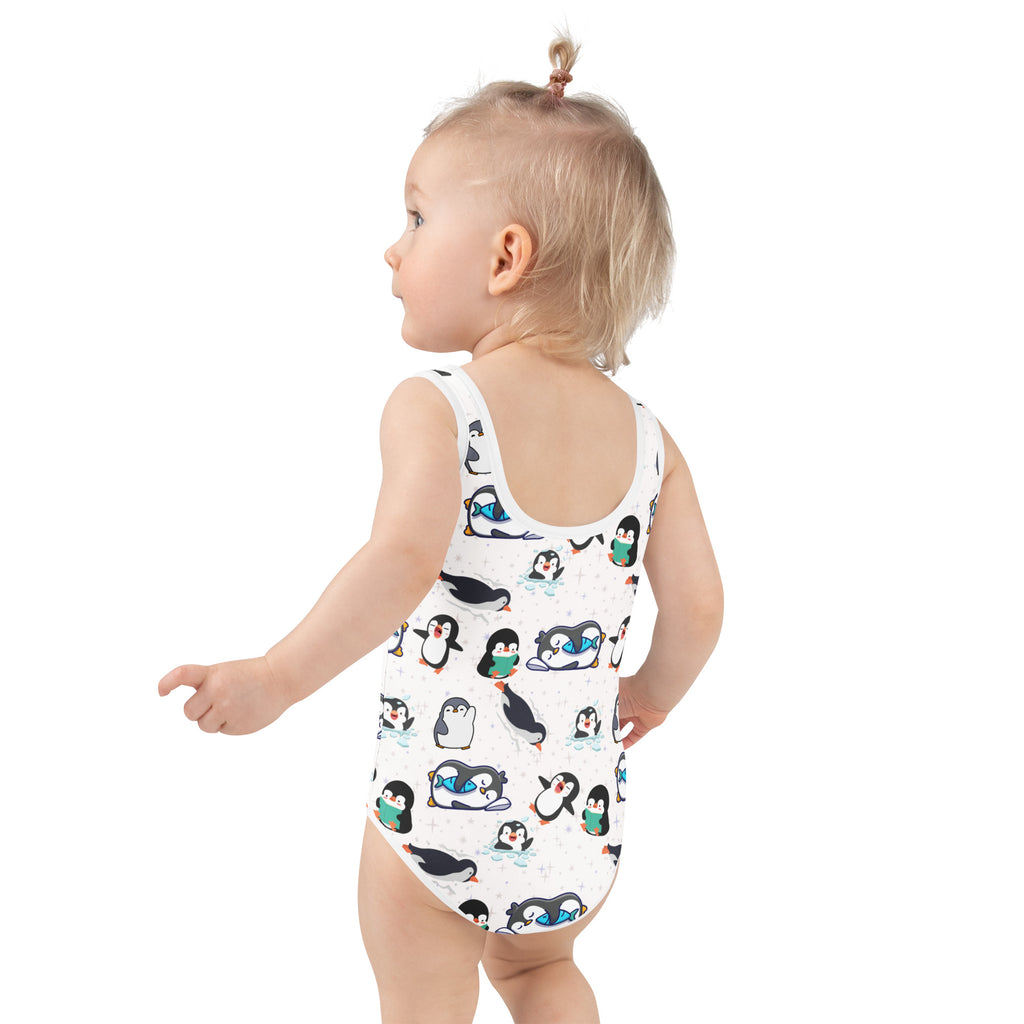 White one-piece girls swimsuit with playful black and white penguin pattern holding green drinks and upf 50+ protection