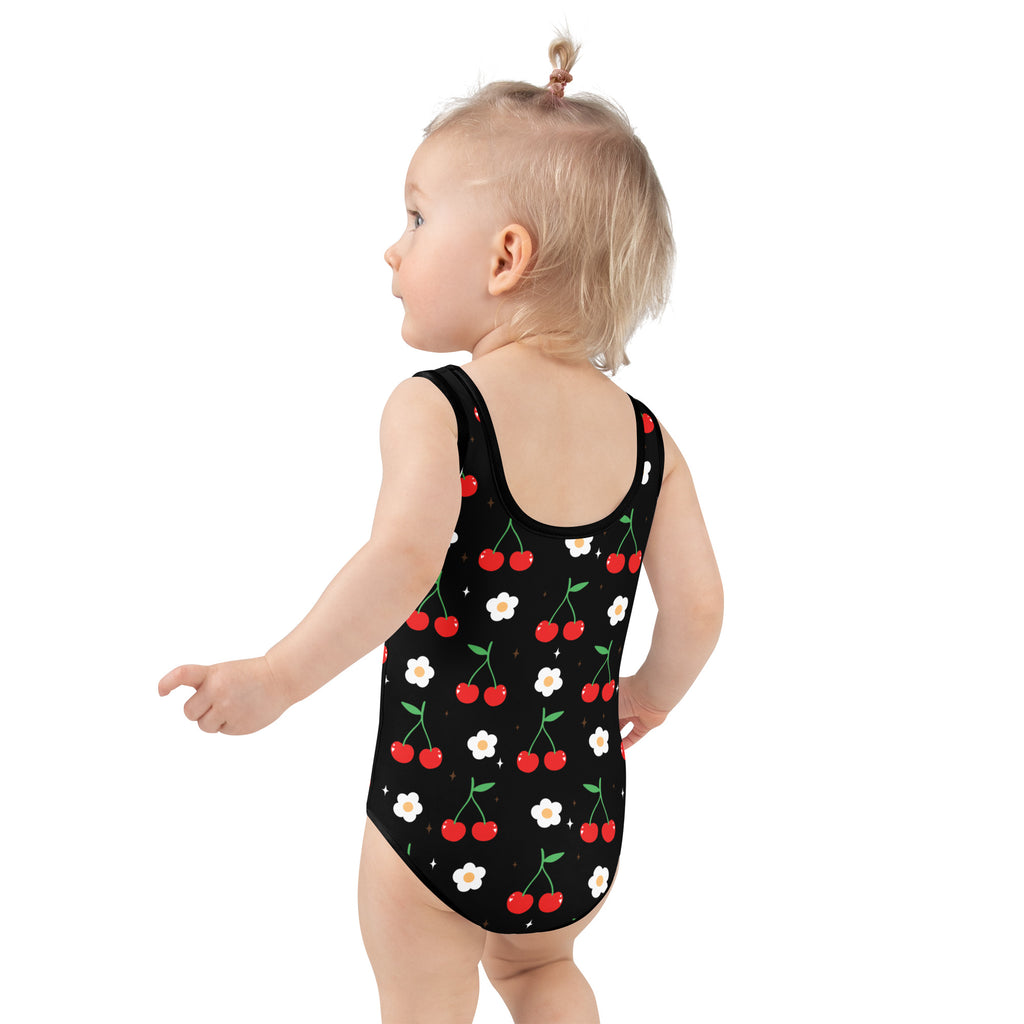 Black one-piece girls swimsuit with a playful red cherry and white daisy pattern and UPF 50 plus buttery soft fabric