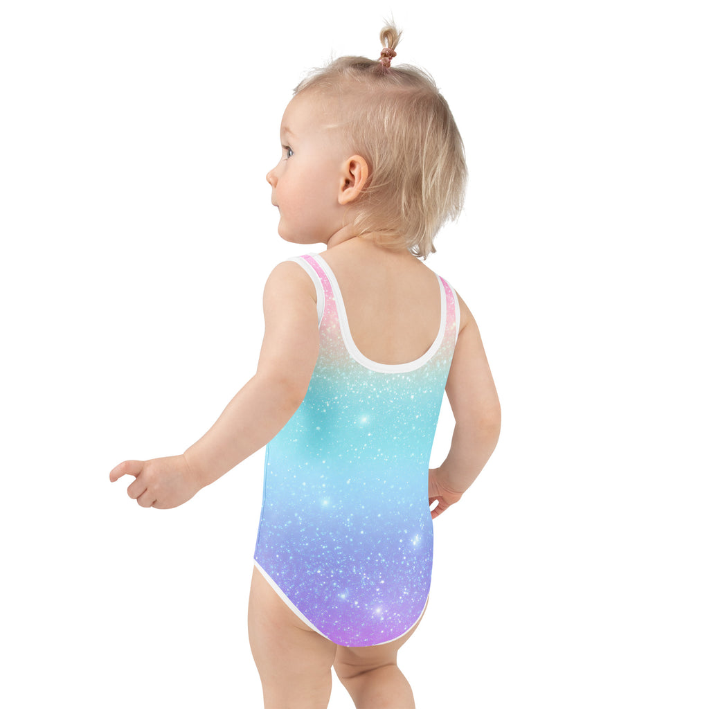 A toddler wearing a girls faux sparkle effect rainbow buttery soft swimsuit with upf 50 plus in galaxy gradient colors