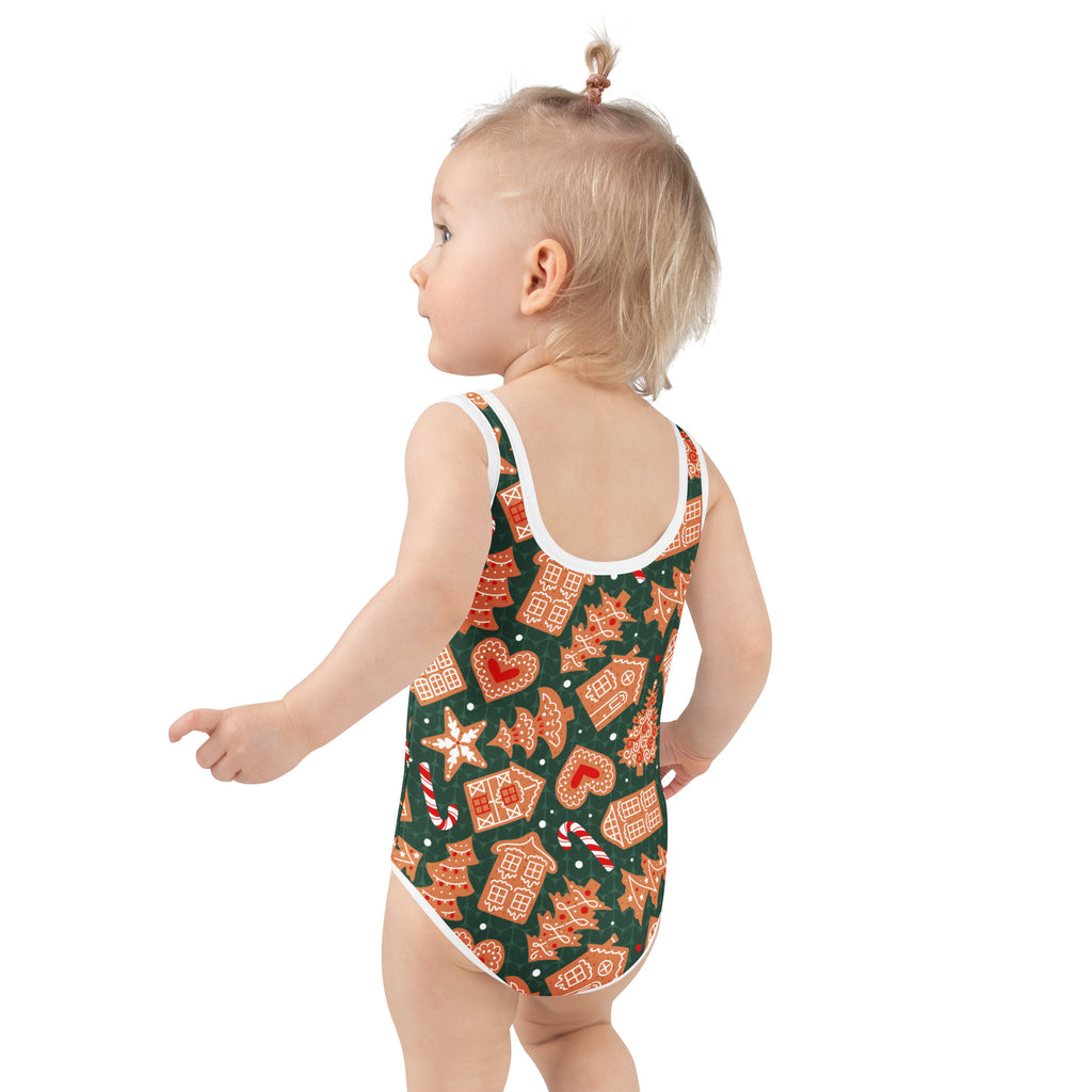 A toddler wearing a girls green gingerbread cookie buttery soft swimsuit with UPF 50 plus and festive patterns