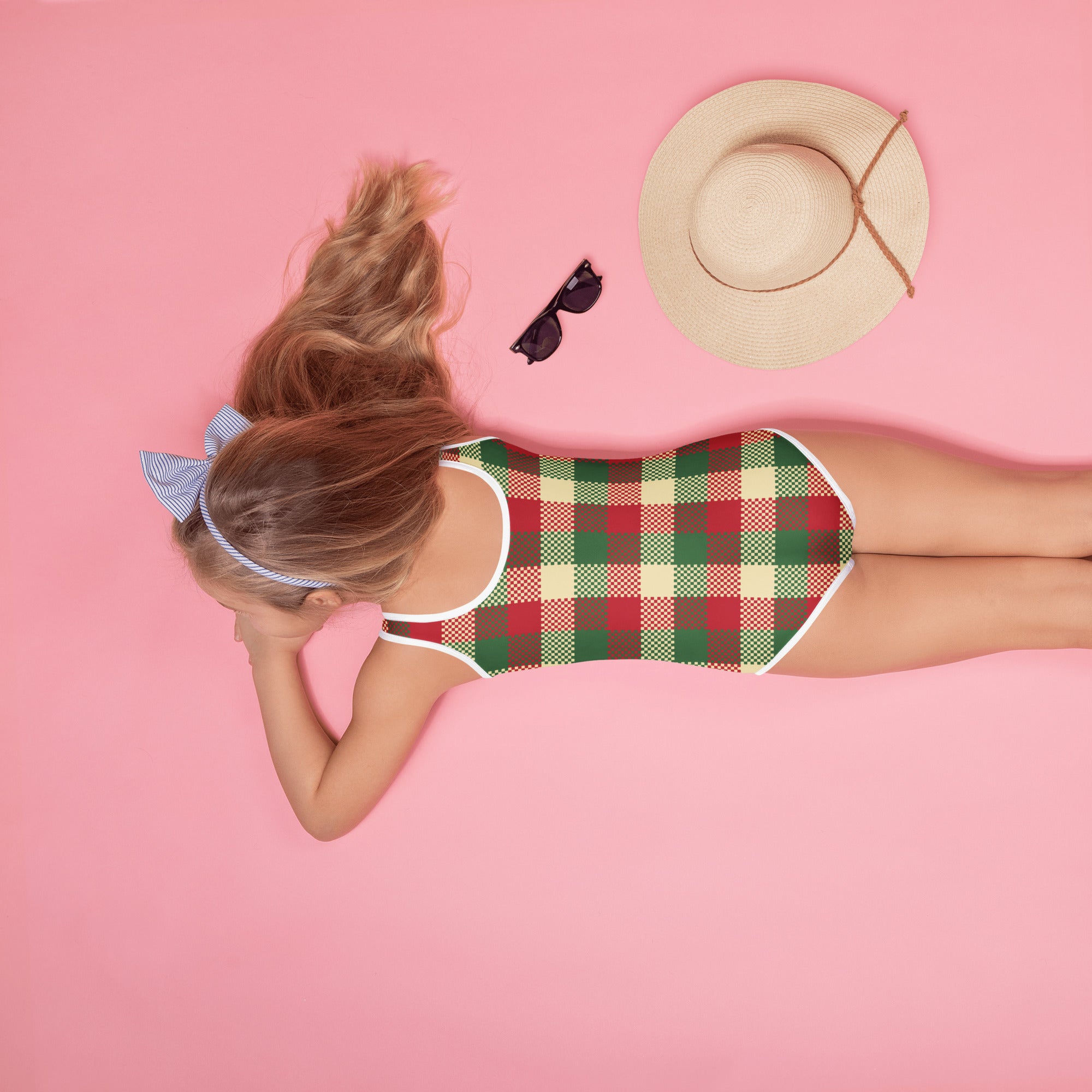 A woman wearing a girls christmas plaid buttery soft swimsuit with UPF 50 plus in red green and cream colors with white trim