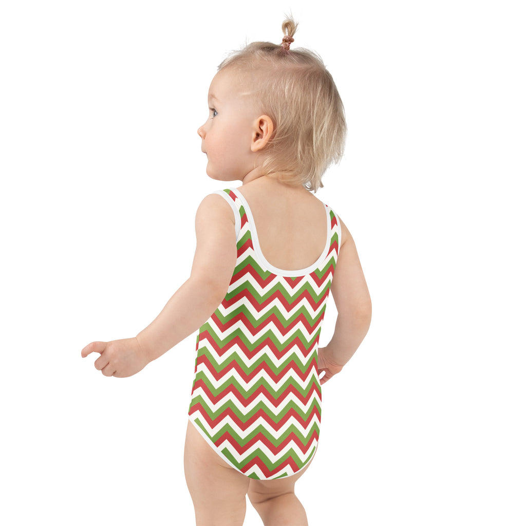 A toddler wearing a girls christmas chevron buttery soft swimsuit in red green and white with UPF 50 plus protection