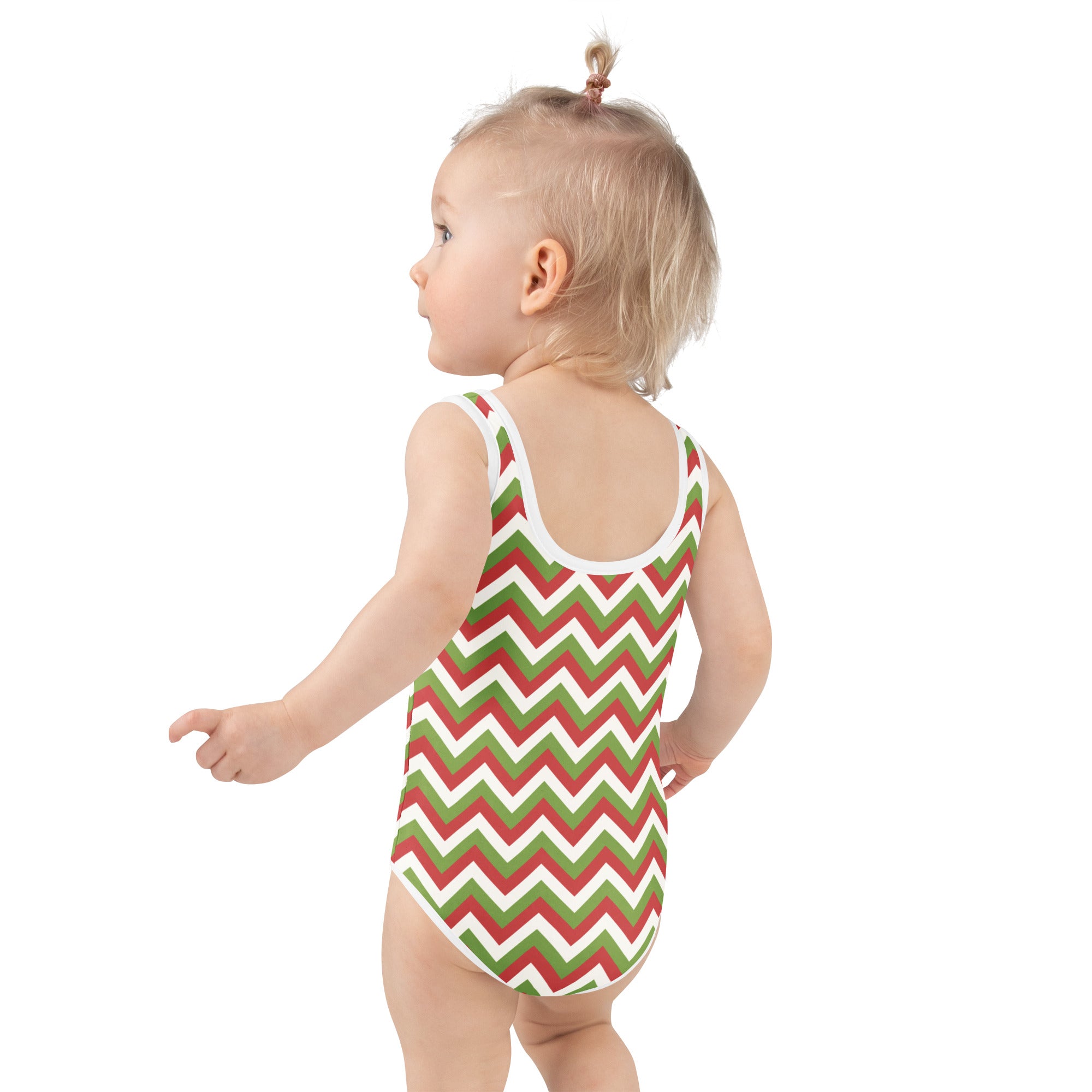 A toddler wearing a girls christmas chevron buttery soft swimsuit in red green and white with UPF 50 plus protection