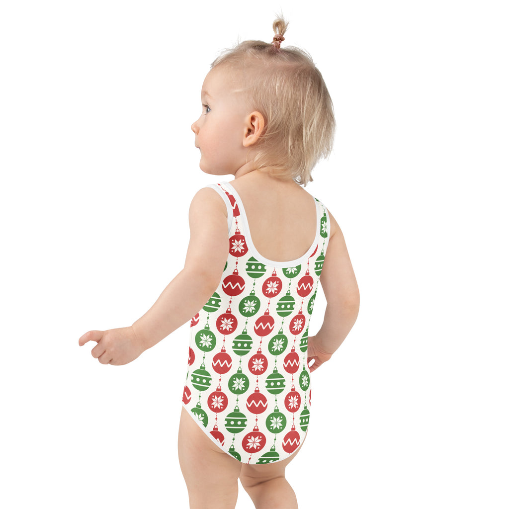 A child wearing a white buttery soft girls christmas ornaments swimsuit with red and green patterns and UPF 50+ protection