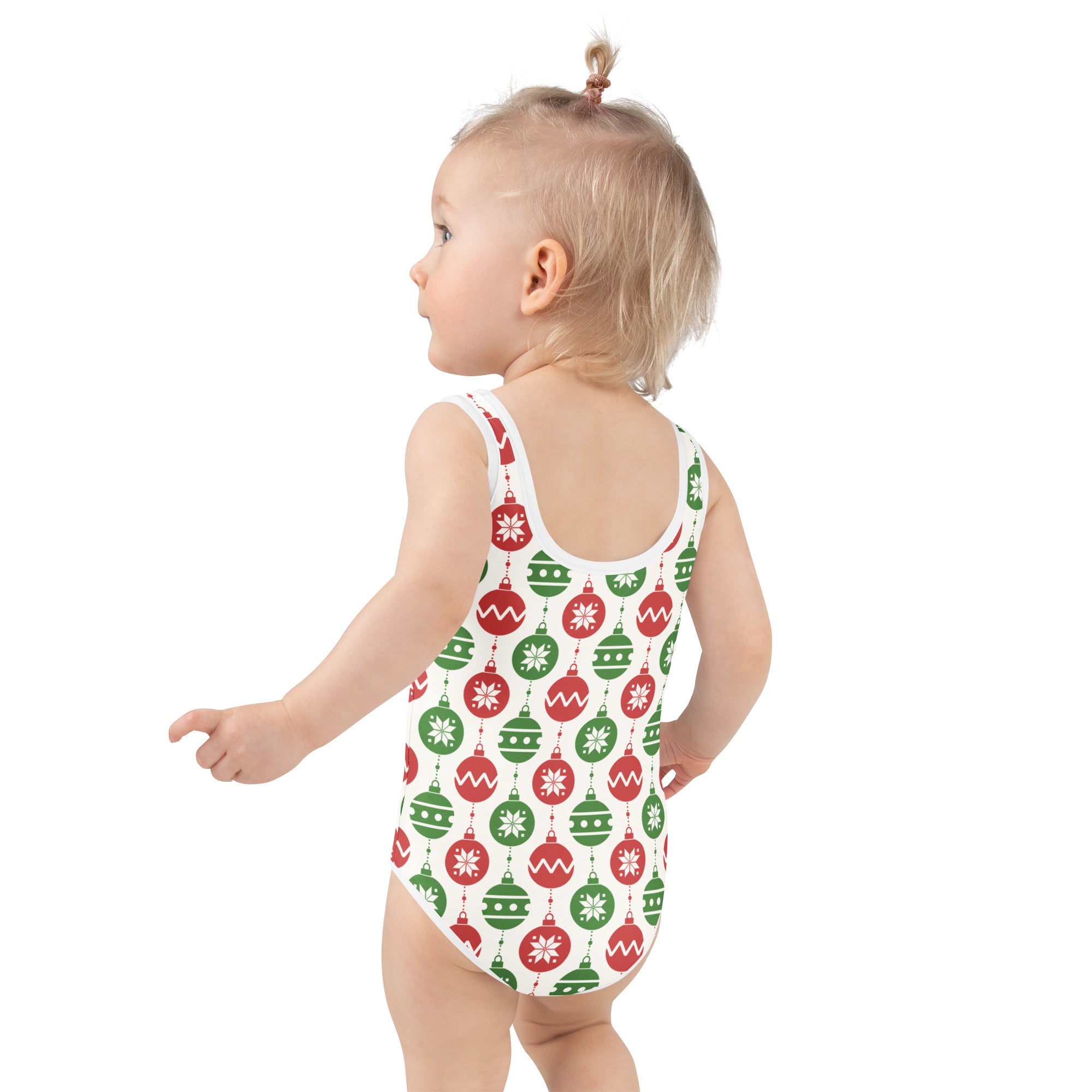 A child wearing a white buttery soft girls christmas ornaments swimsuit with red and green patterns and UPF 50+ protection