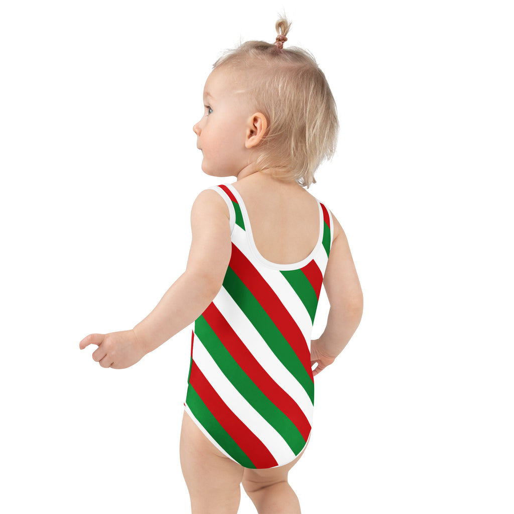 A toddler wearing a girls candy cane striped christmas buttery soft swimsuit with upf 50 plus in red and green