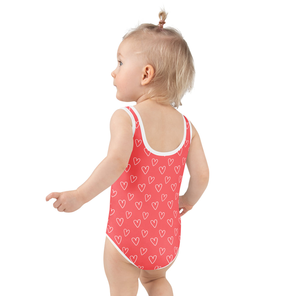 A coral girls day heart outline buttery soft one-piece swimsuit with white trim and UPF 50 plus double layered front