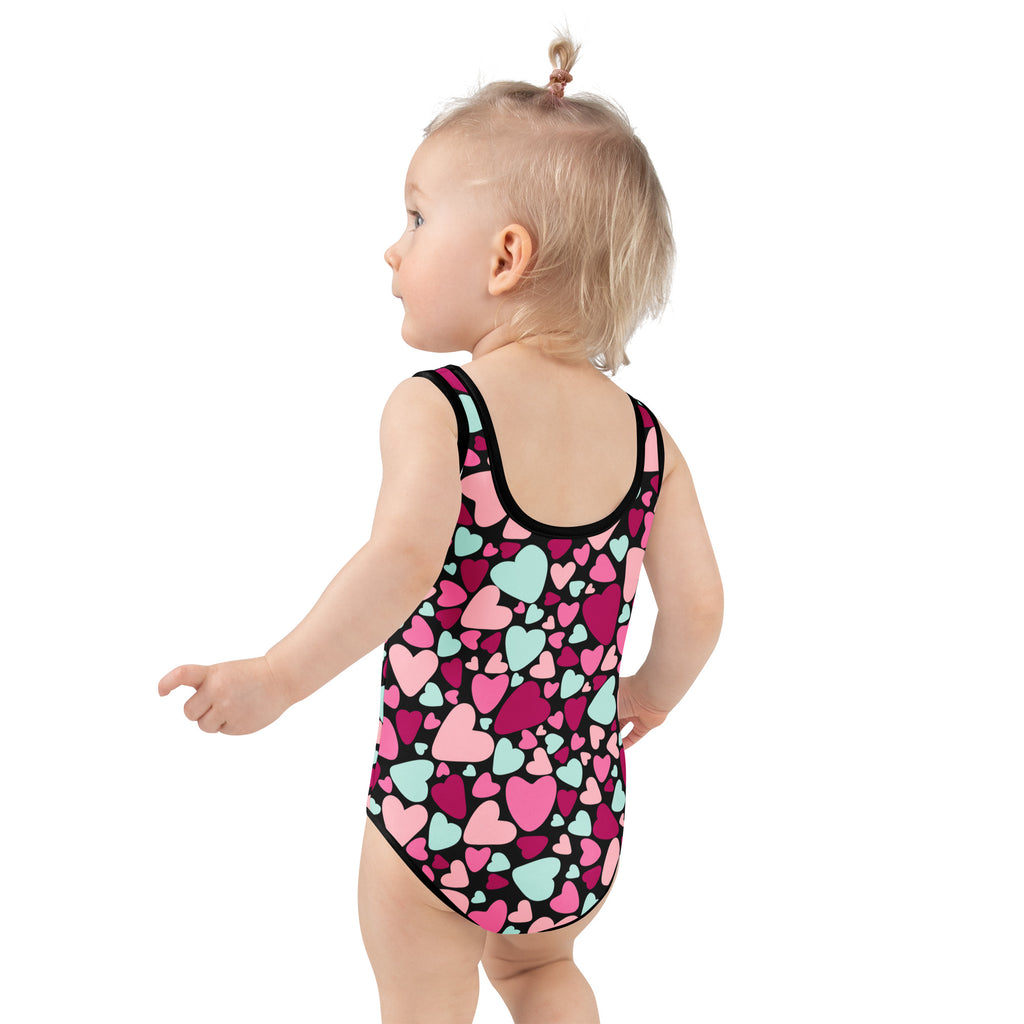A girl wearing a girls Valentine’s Day colorful heart buttery soft swimsuit with UPF 50+ and double layered front