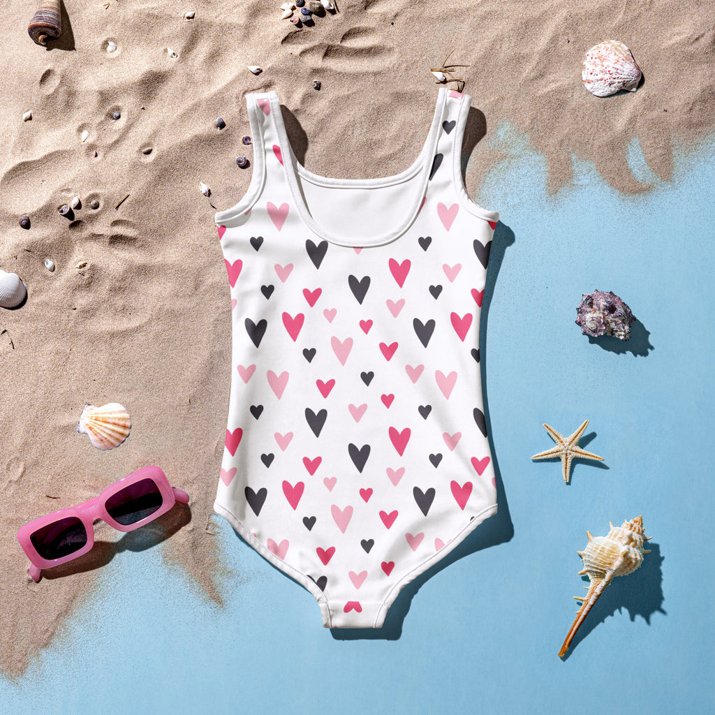 A white girls Valentine’s Day heart buttery soft swimsuit with black and pink hearts and UPF 50+ protection