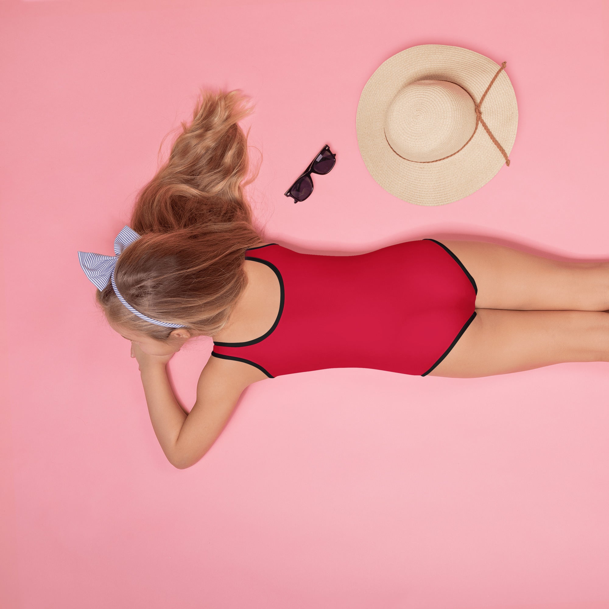 A vibrant red girls ruby red buttery soft one-piece swimsuit with black trim and UPF 50 plus protection