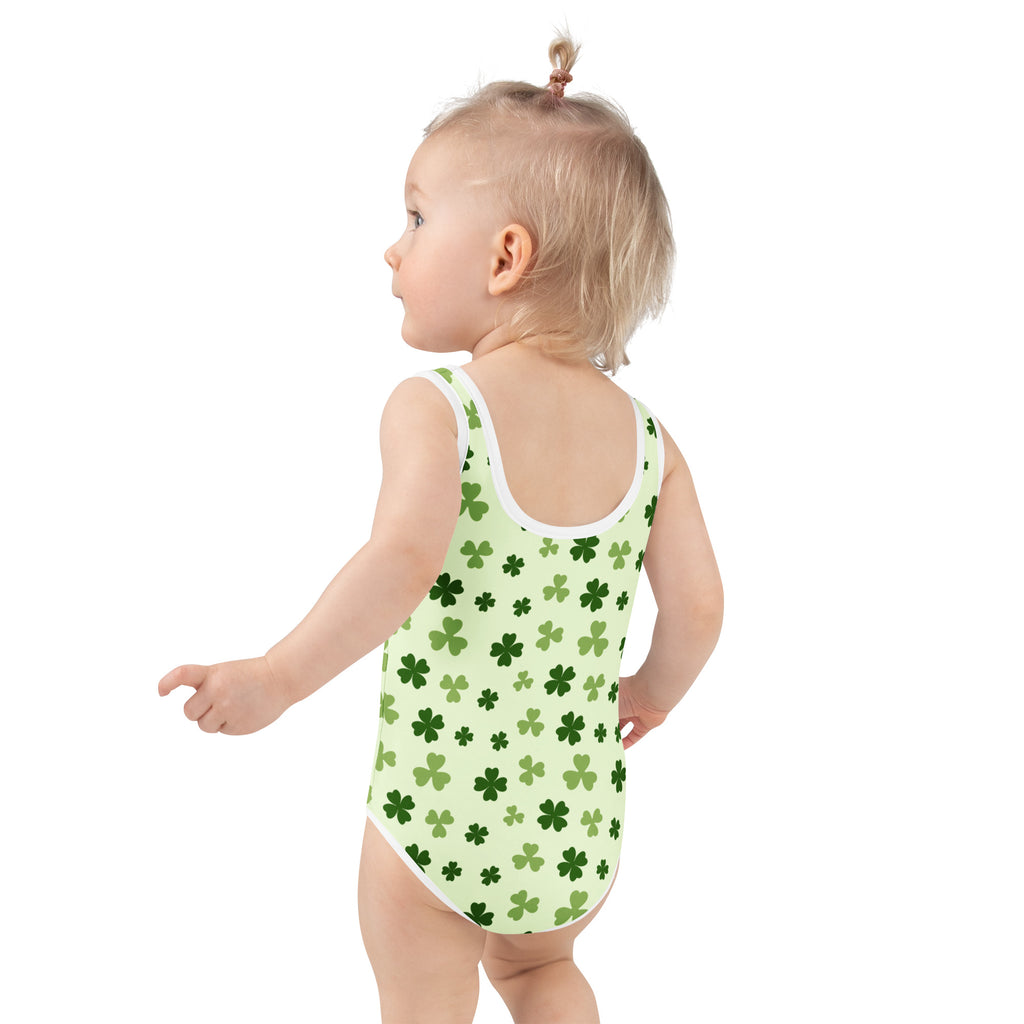 A baby girl wearing a girls light green shamrock buttery soft swimsuit with upf 50 plus and double layered front