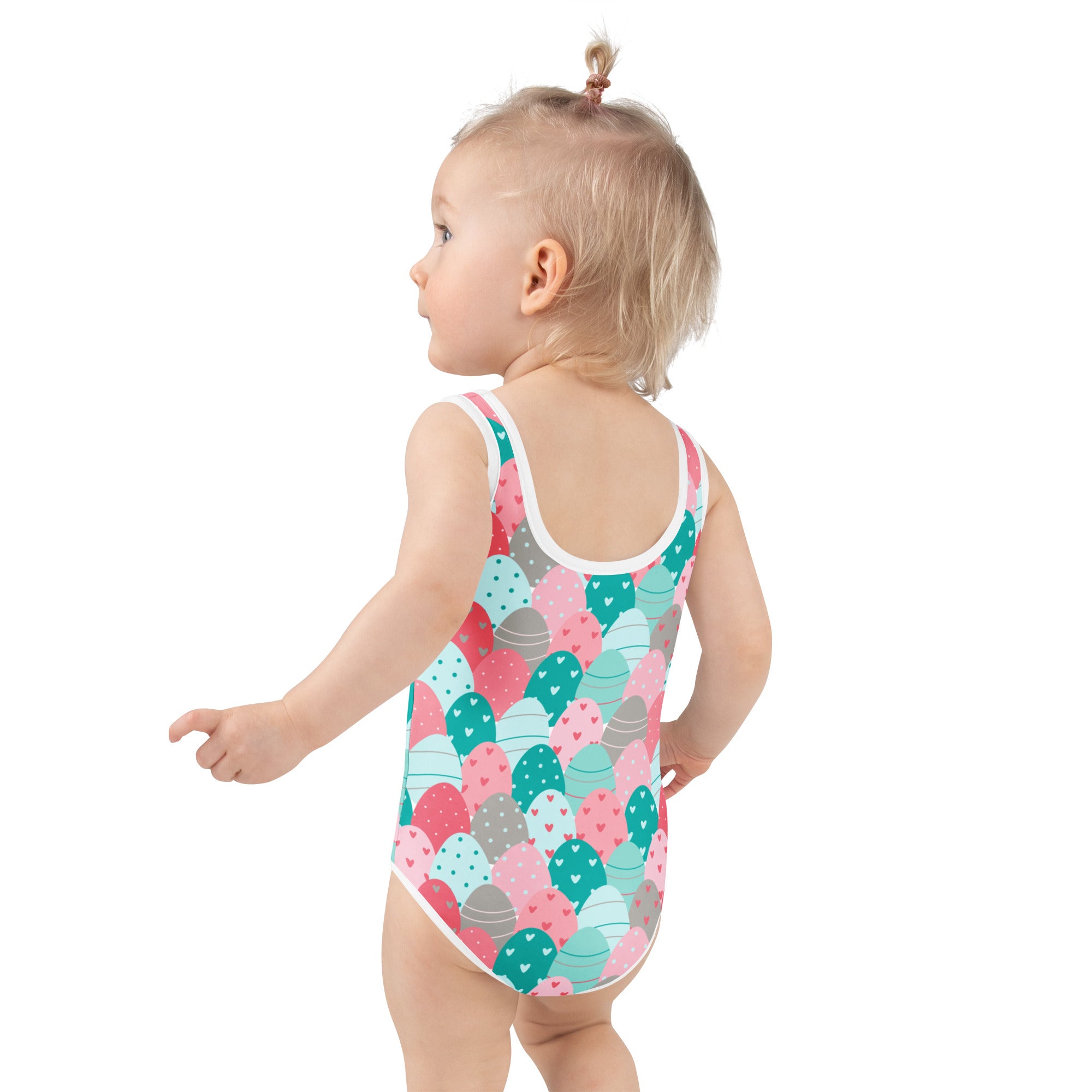 A toddler wearing a girls Easter eggs buttery soft pastel heart dotted swimsuit with UPF 50 plus and double layered front